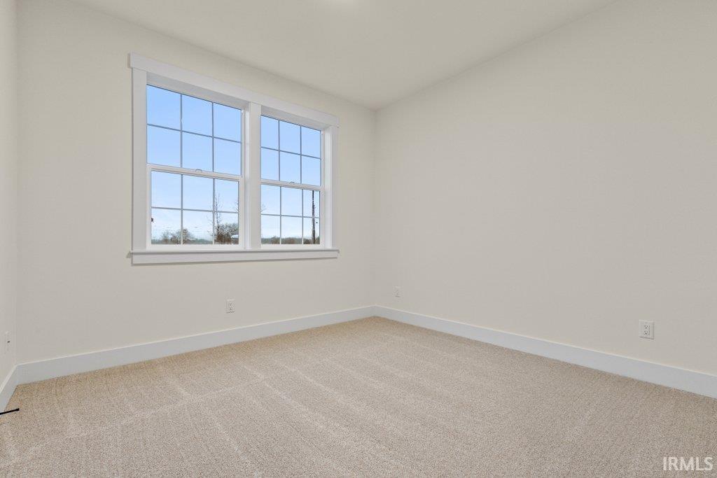 Empty room featuring light carpet and baseboards