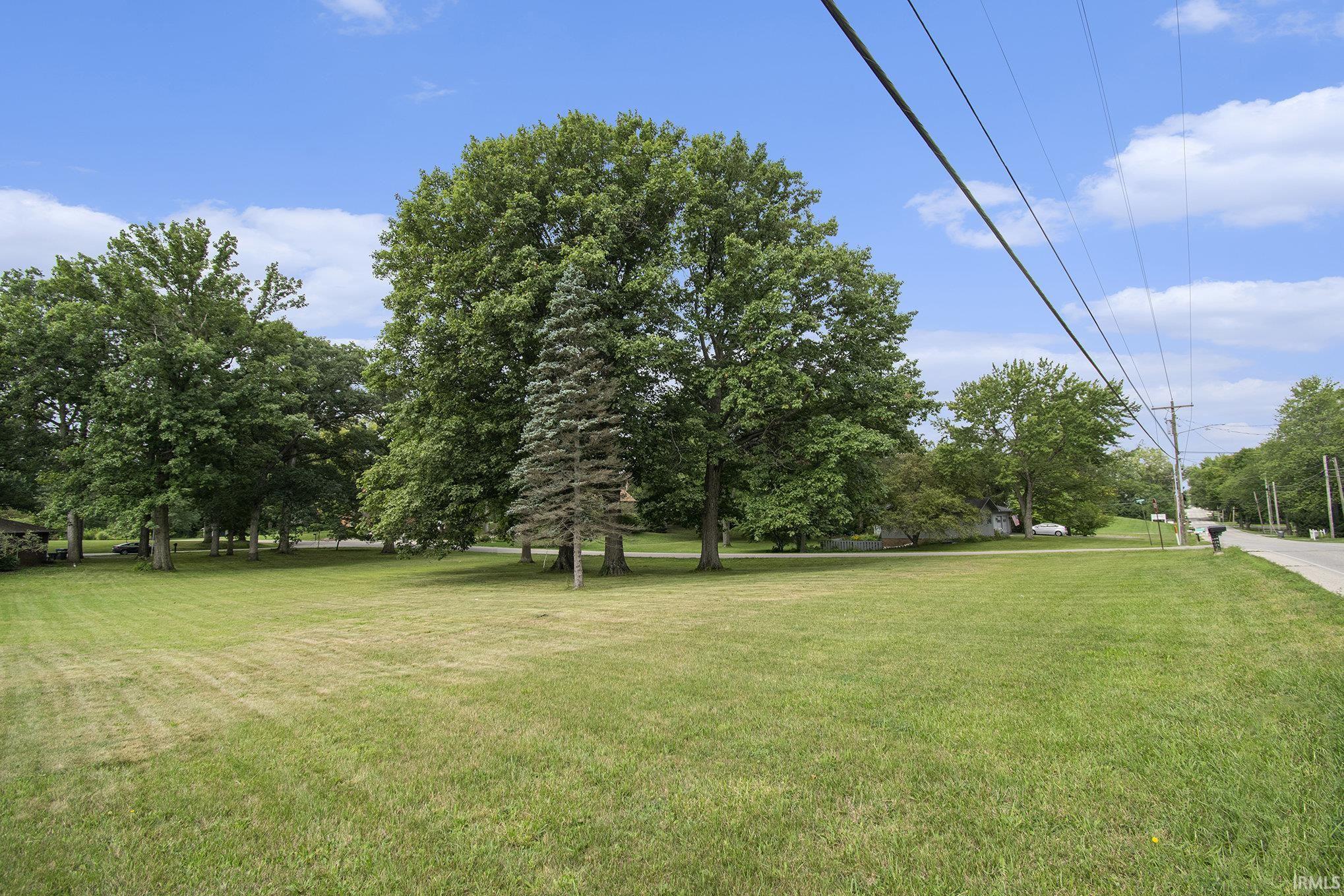 View of green lawn featuring view of wooded area