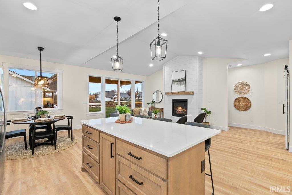 Kitchen featuring a breakfast bar area, a kitchen island, vaulted ceiling, decorative light fixtures, and open floor plan