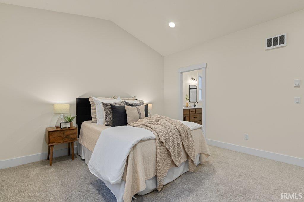 Bedroom with vaulted ceiling, recessed lighting, ensuite bath, and light colored carpet