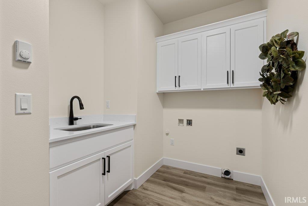 Laundry room with cabinet space, light wood-style floors, hookup for an electric dryer, hookup for a washing machine, and hookup for a gas dryer