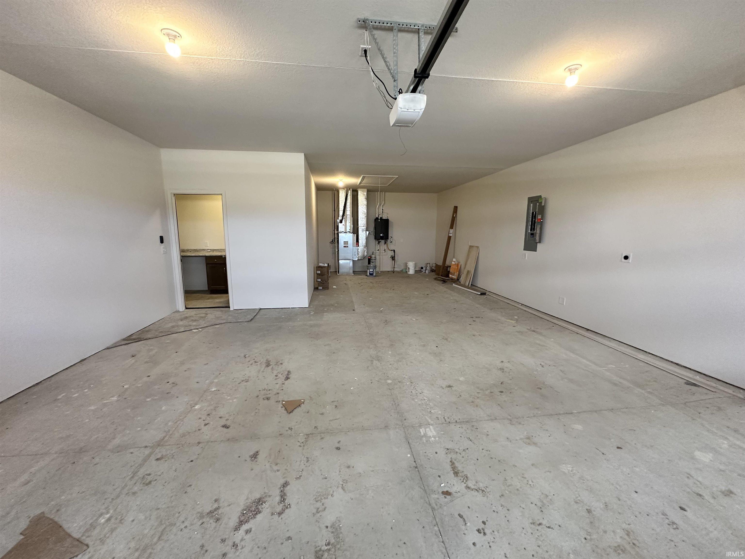 Garage with electric panel, heating unit, and a garage door opener