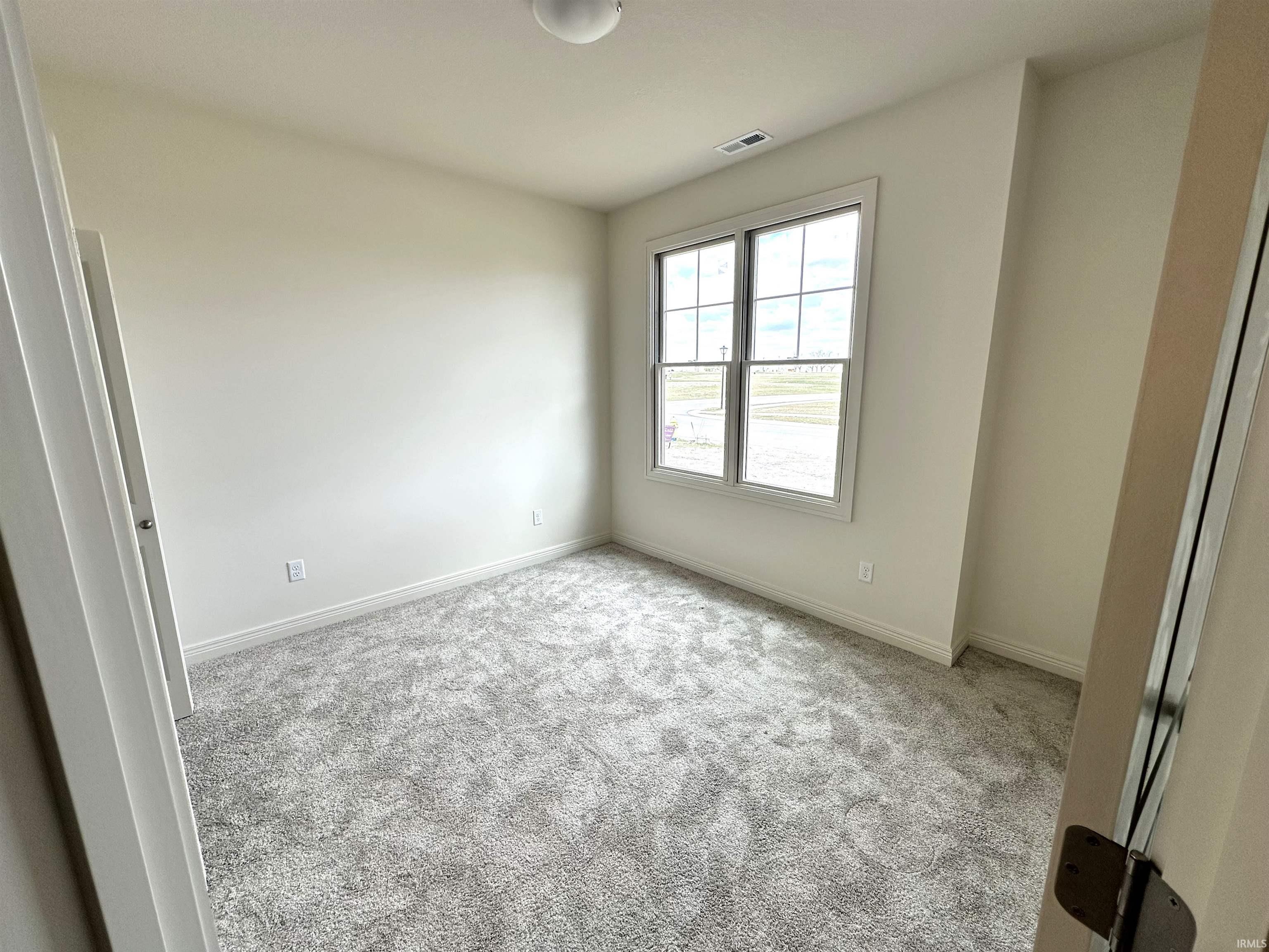 Unfurnished bedroom featuring light carpet and baseboards