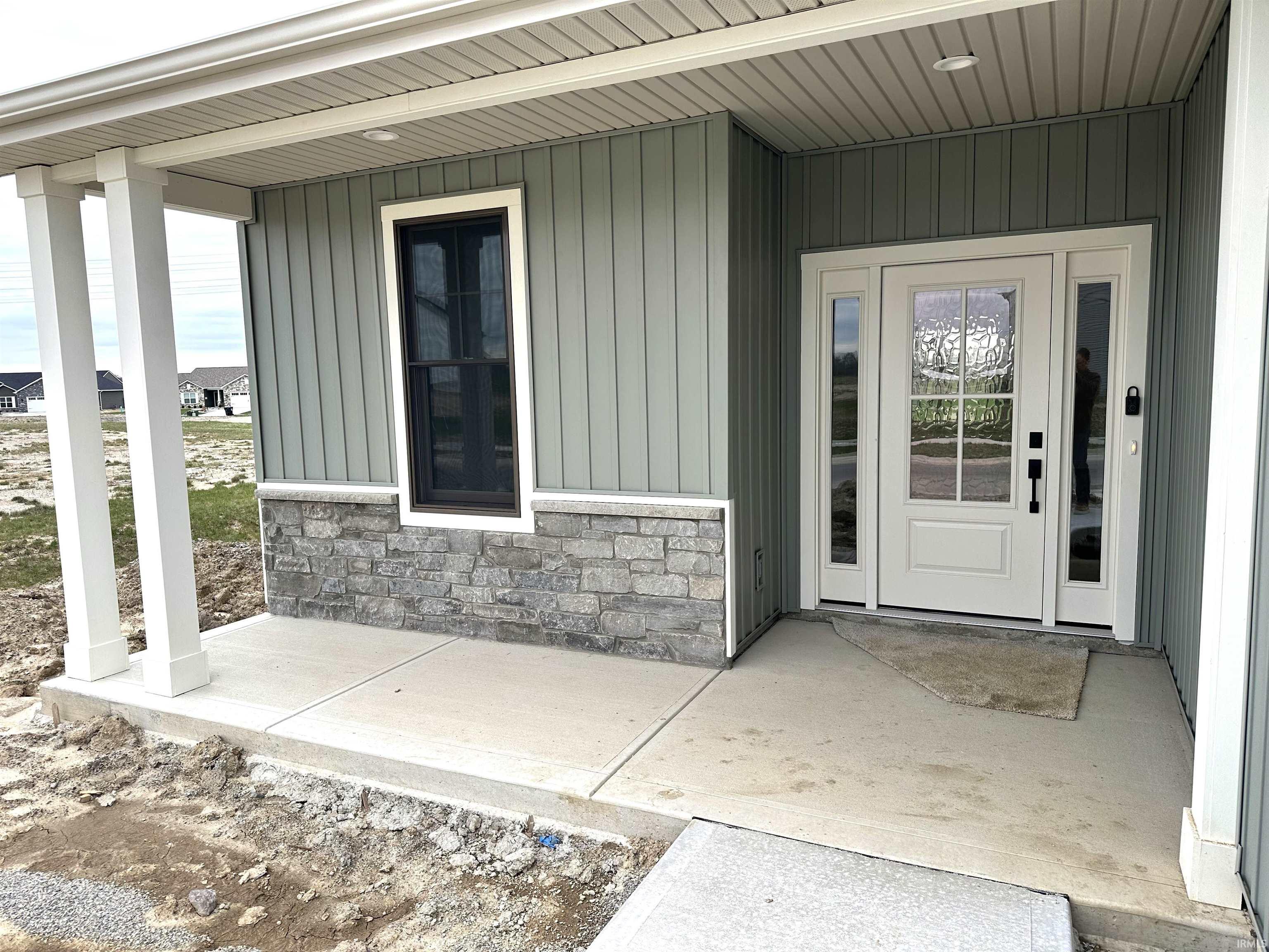 Doorway to property with a porch, stone siding, and board and batten siding