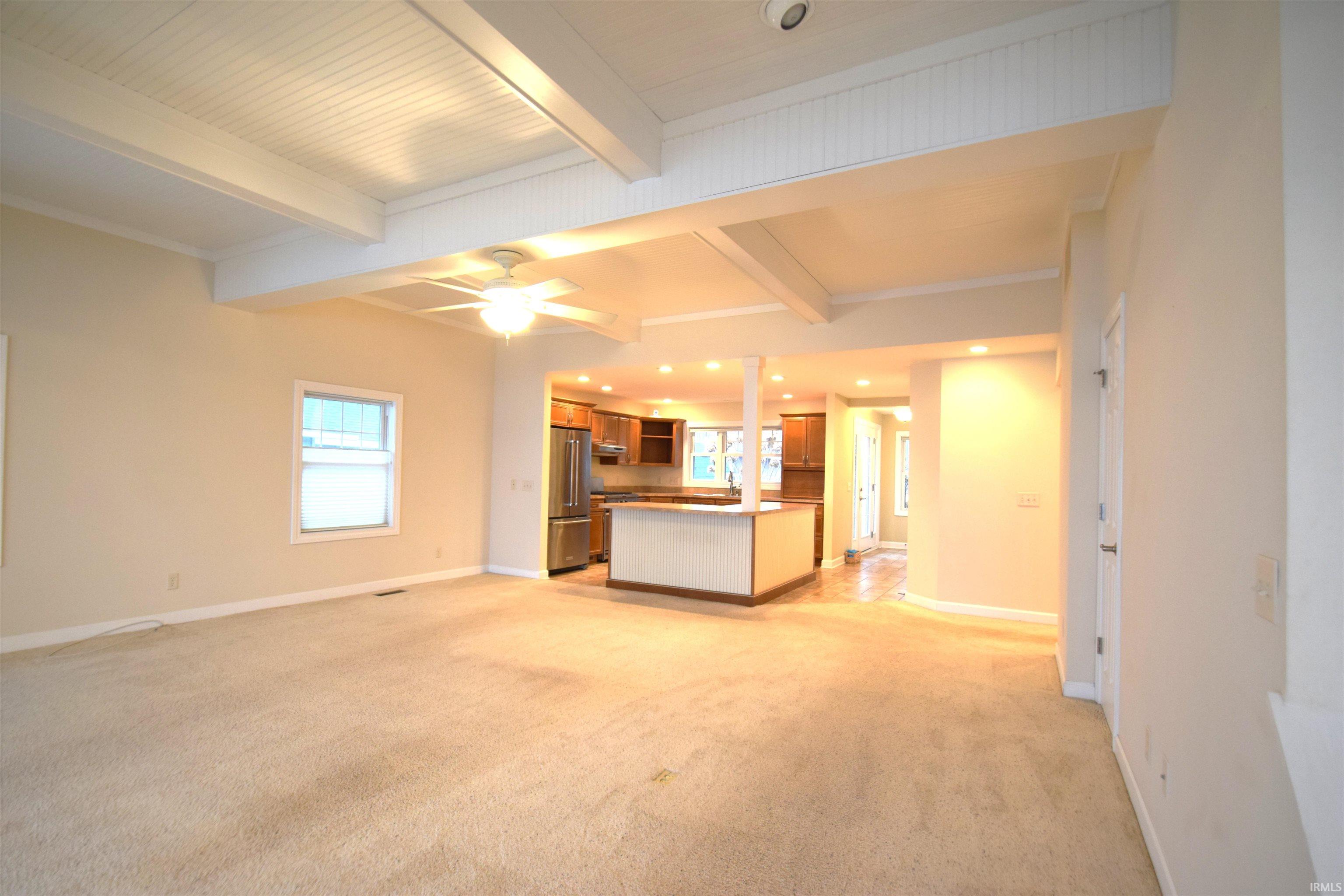 Unfurnished living room with beamed ceiling, healthy amount of natural light, light carpet, a ceiling fan, and recessed lighting