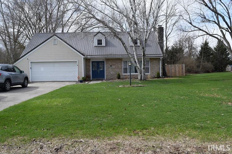View of front of home featuring a front yard, a metal roof, an attached garage, and concrete driveway
