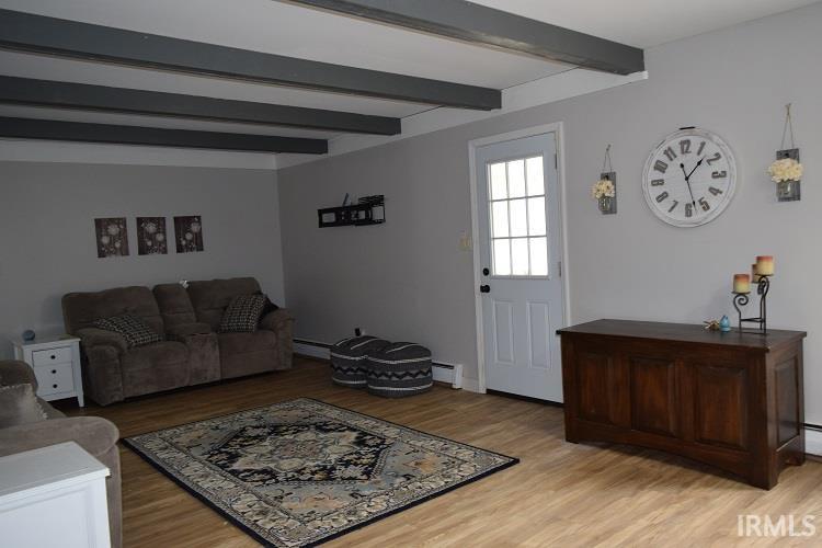 Living room featuring light wood-style flooring, beamed ceiling, and a baseboard heating unit