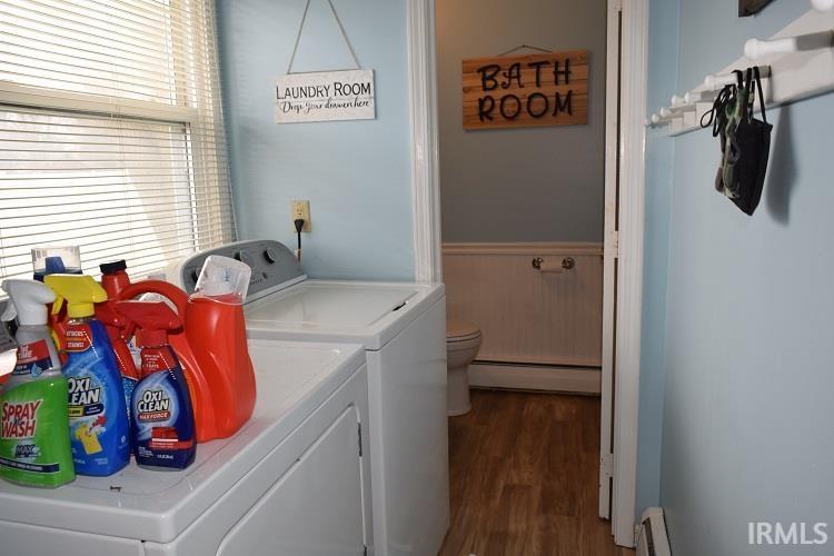 Laundry area with dark wood finished floors, separate washer and dryer, a baseboard heating unit, baseboard heating, and a wainscoted wall