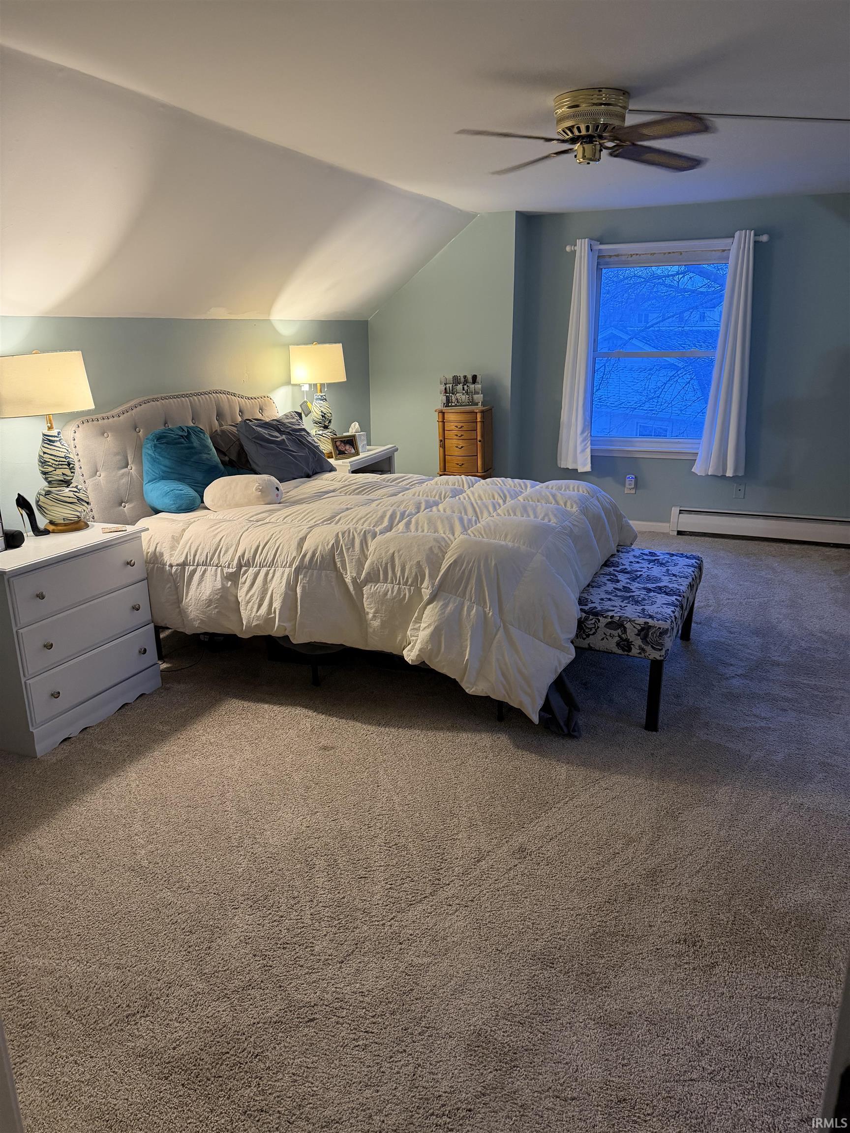 Bedroom with lofted ceiling, carpet, a baseboard radiator, and a ceiling fan