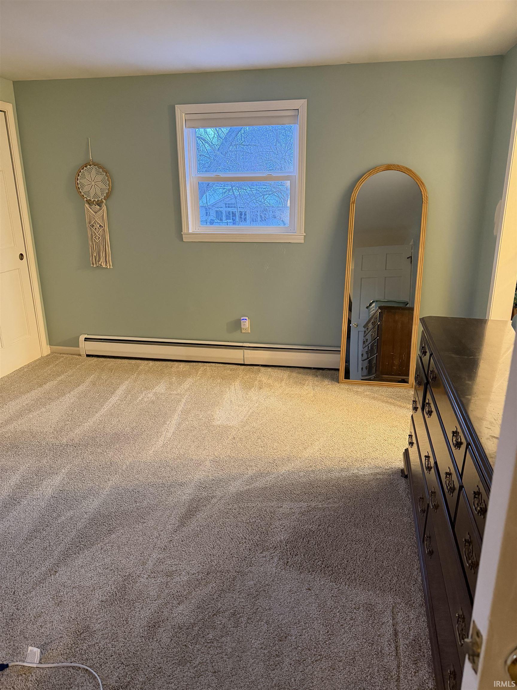 bedroom with light colored carpet and a baseboard radiator