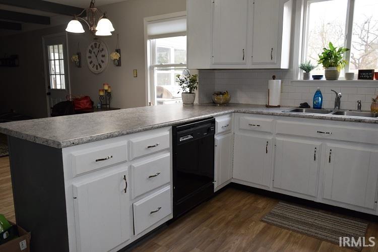 Kitchen featuring white cabinets, a peninsula, dark wood-style floors, and light countertops