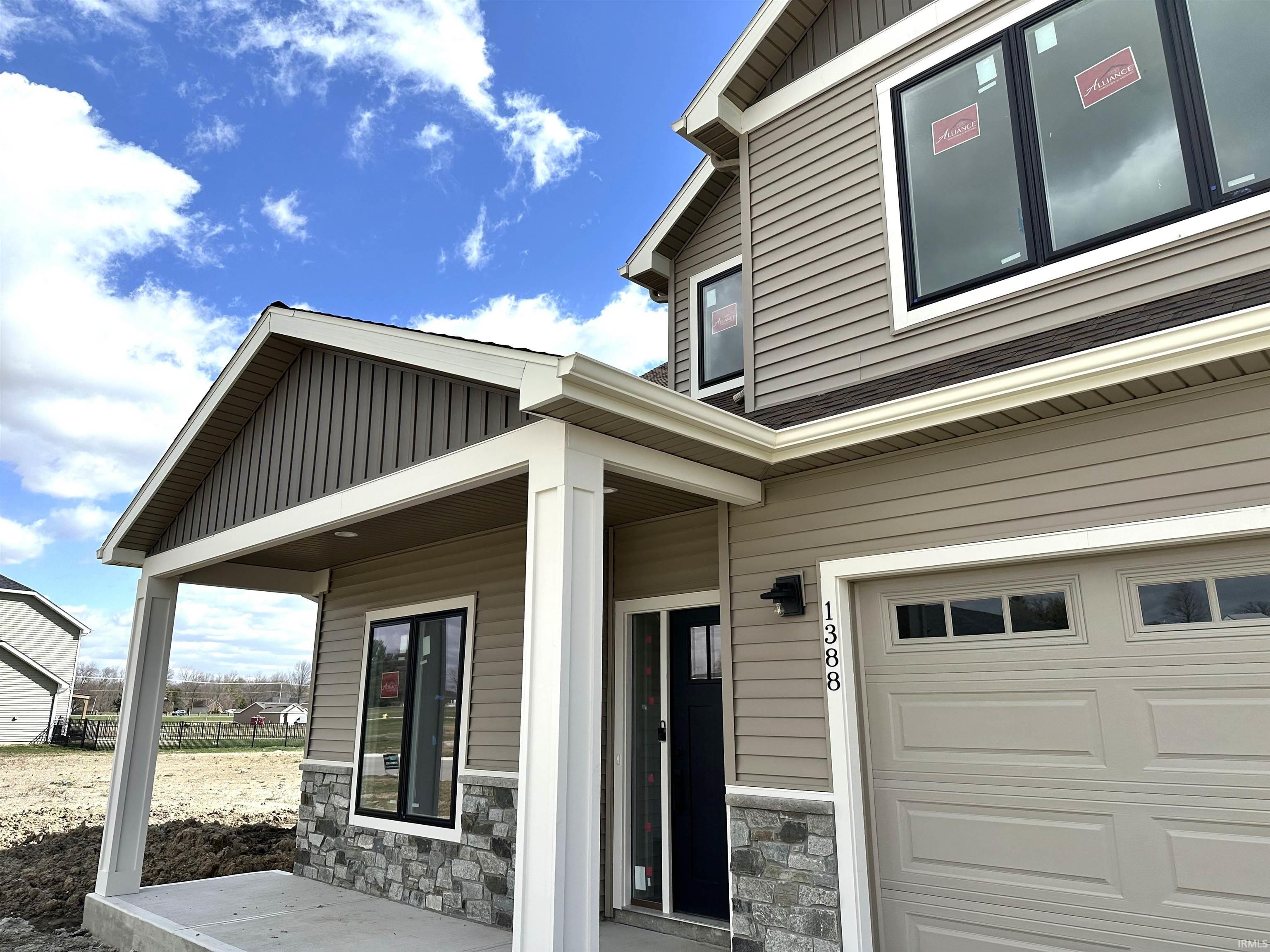 Property entrance with a porch, board and batten siding, stone siding, and a garage