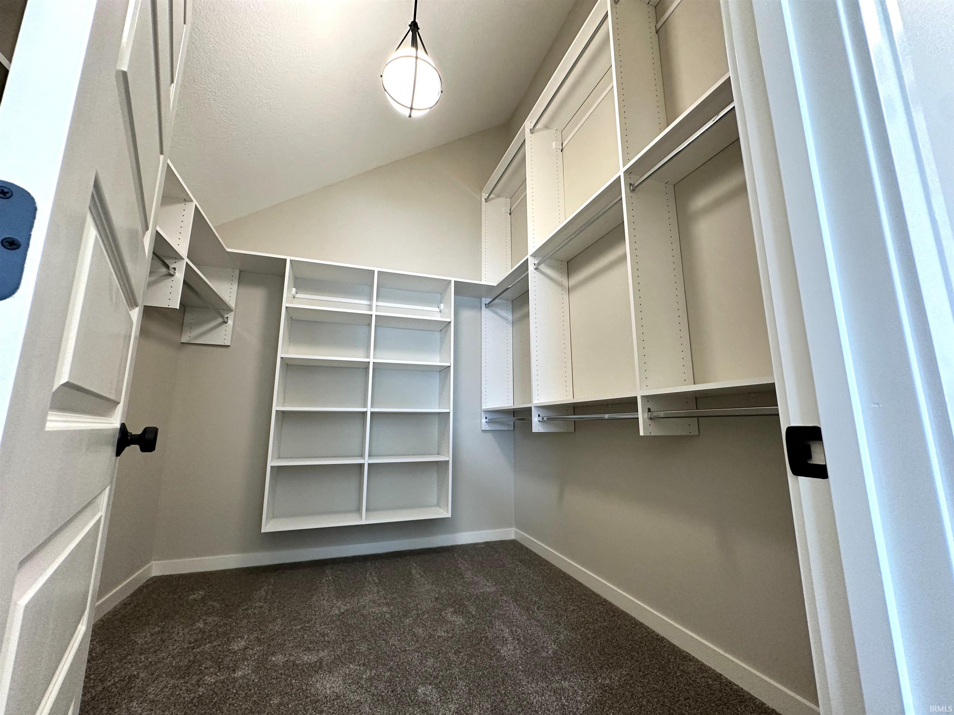 Walk in closet with dark colored carpet and vaulted ceiling