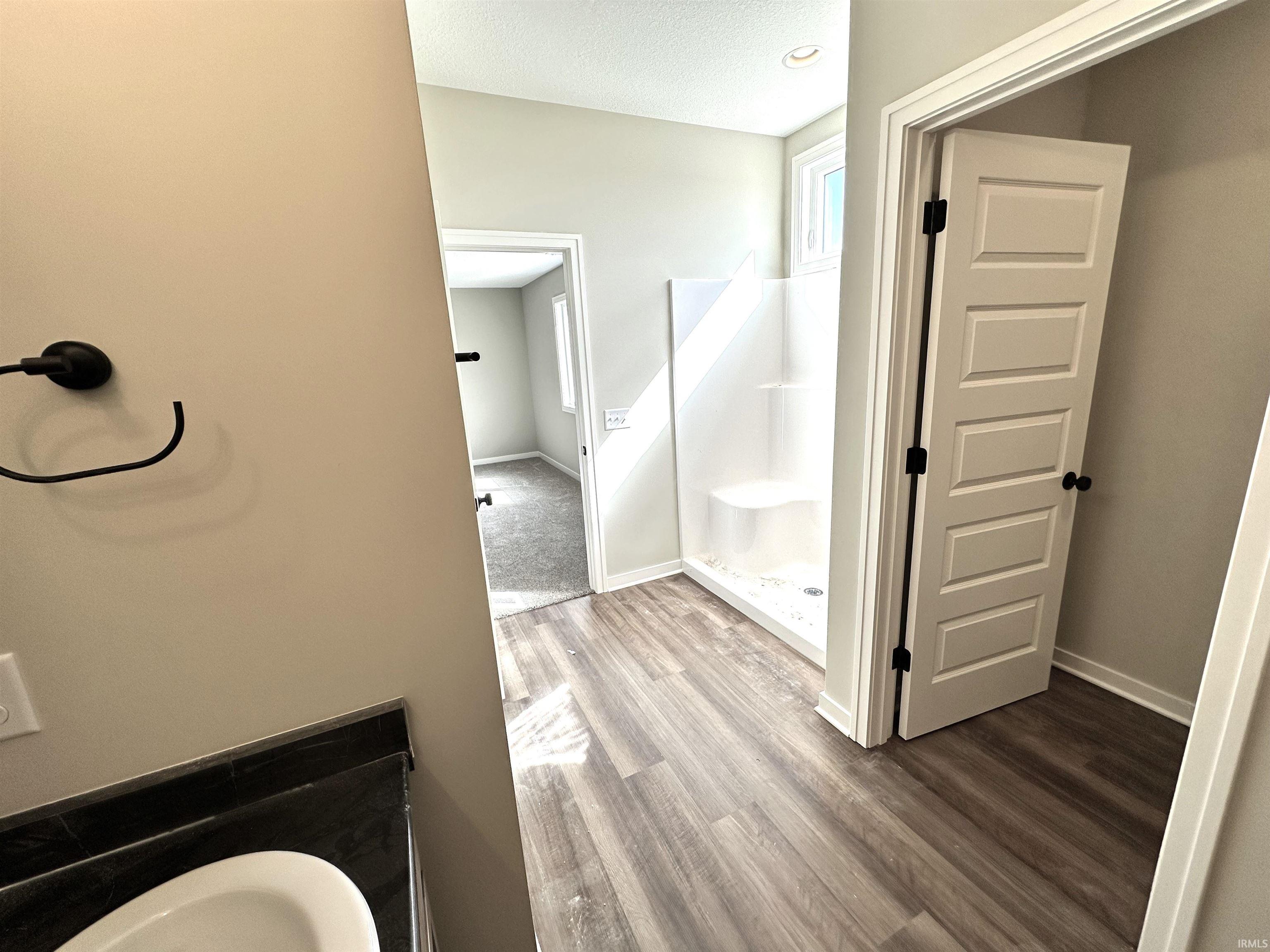 Bathroom with a shower stall, wood finished floors, and a textured ceiling