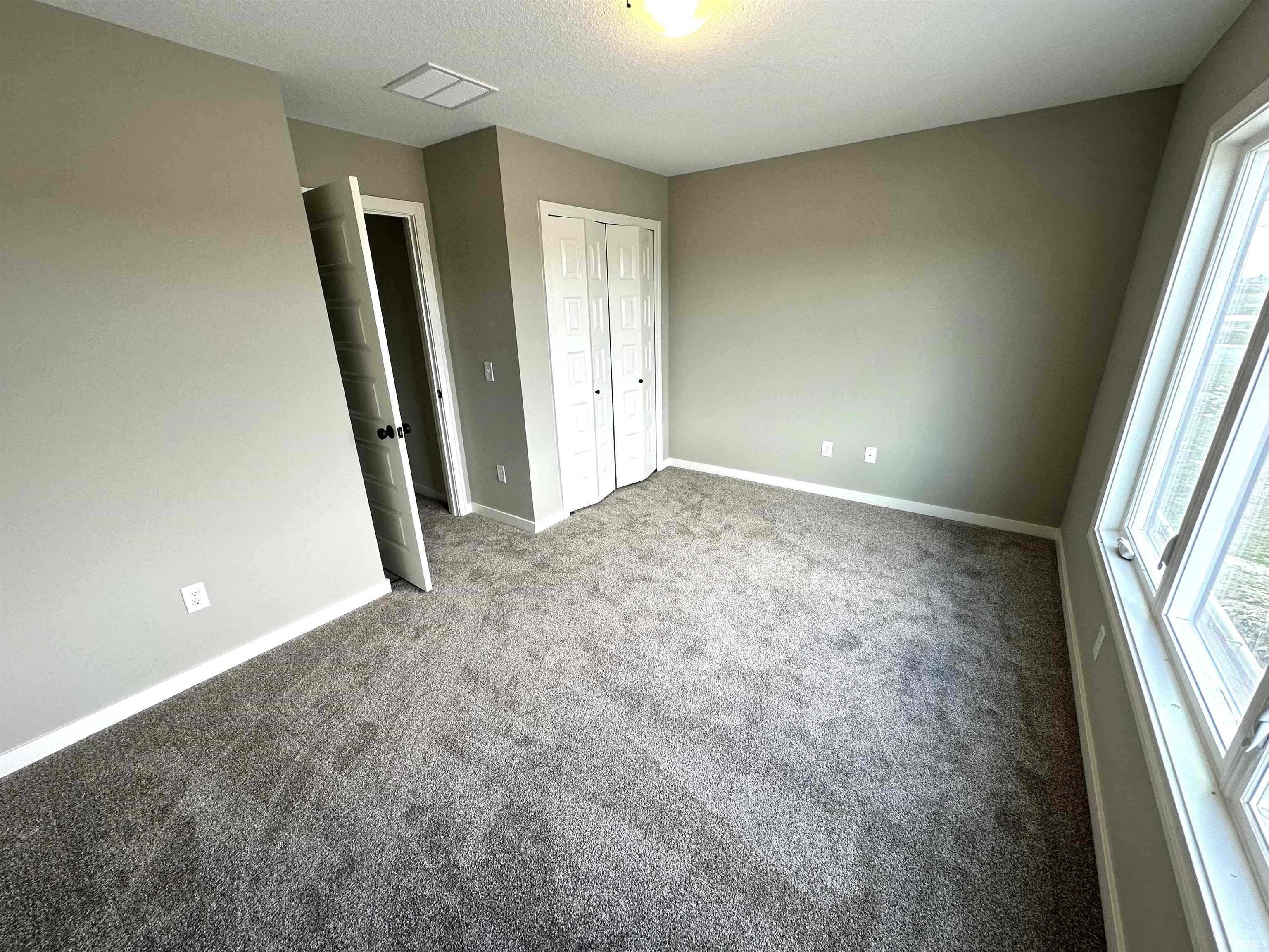Unfurnished bedroom with light carpet, a closet, and a textured ceiling