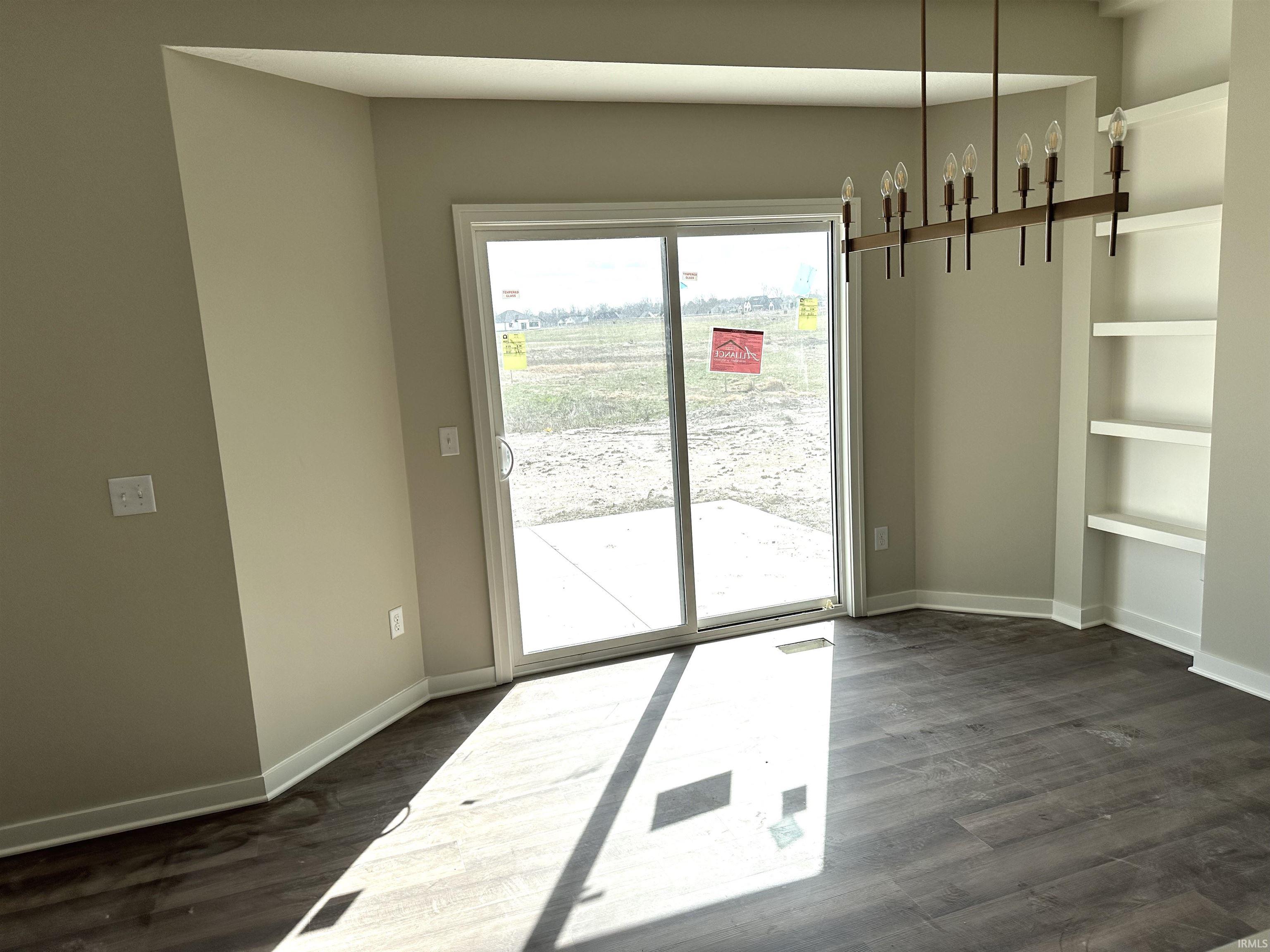 Unfurnished dining area featuring dark wood-type flooring and built in shelves