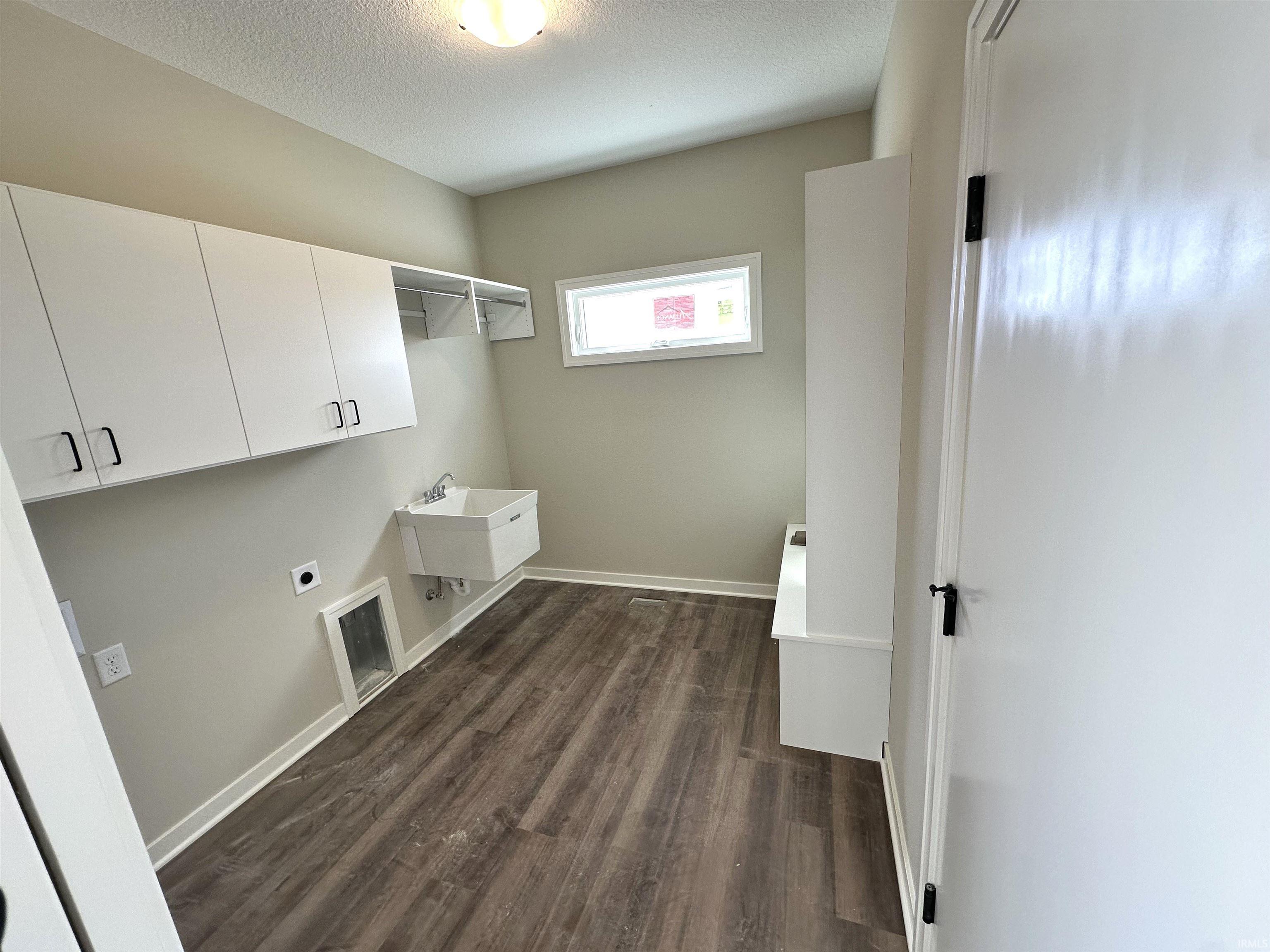 Laundry room featuring cabinet space, dark wood-type flooring, a textured ceiling, and hookup for an electric dryer