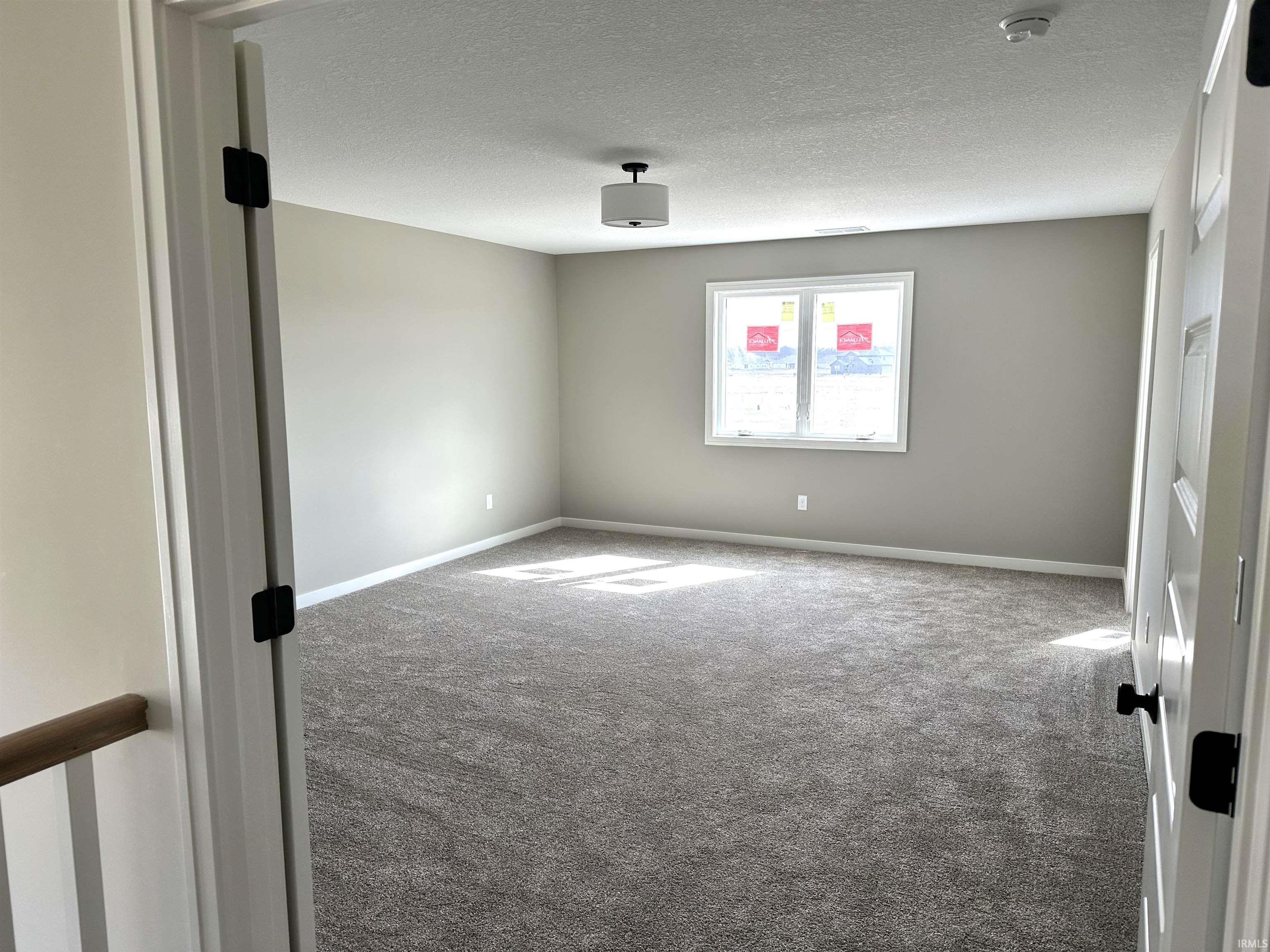 Carpeted empty room with a textured ceiling and baseboards