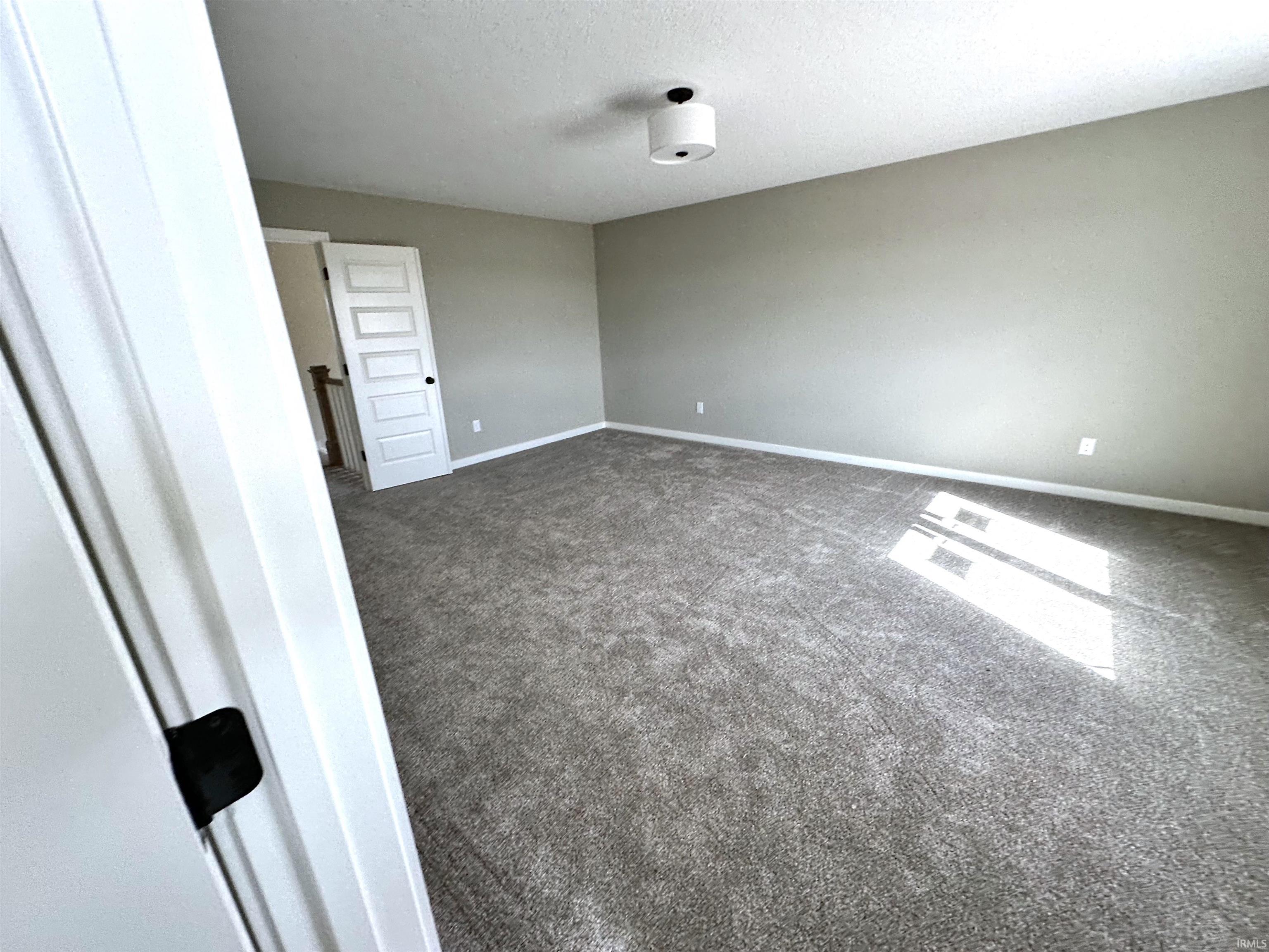 Spare room featuring dark carpet and a textured ceiling