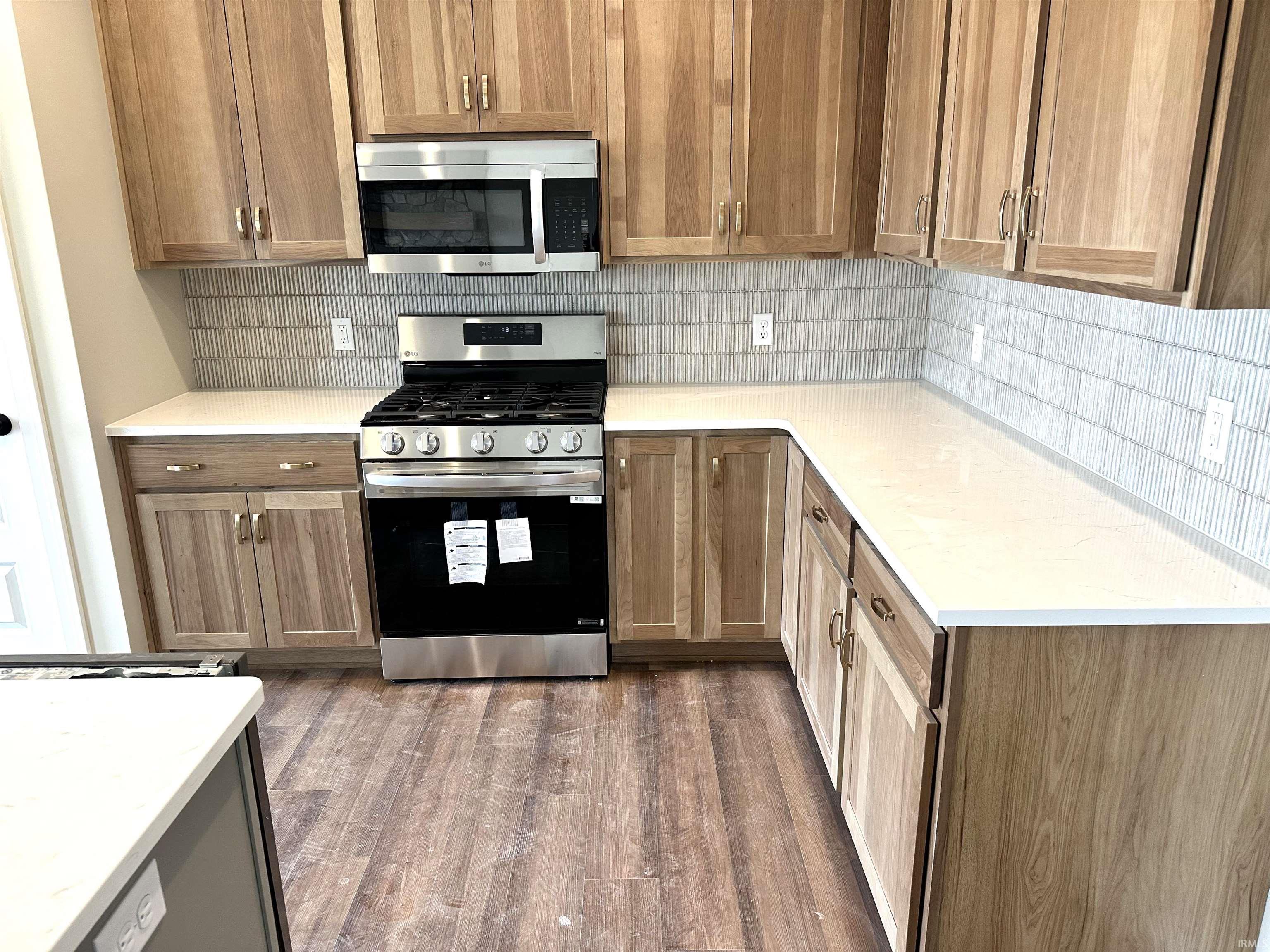 Kitchen with stainless steel appliances, backsplash, dark wood-type flooring, and wood finish cabinets
