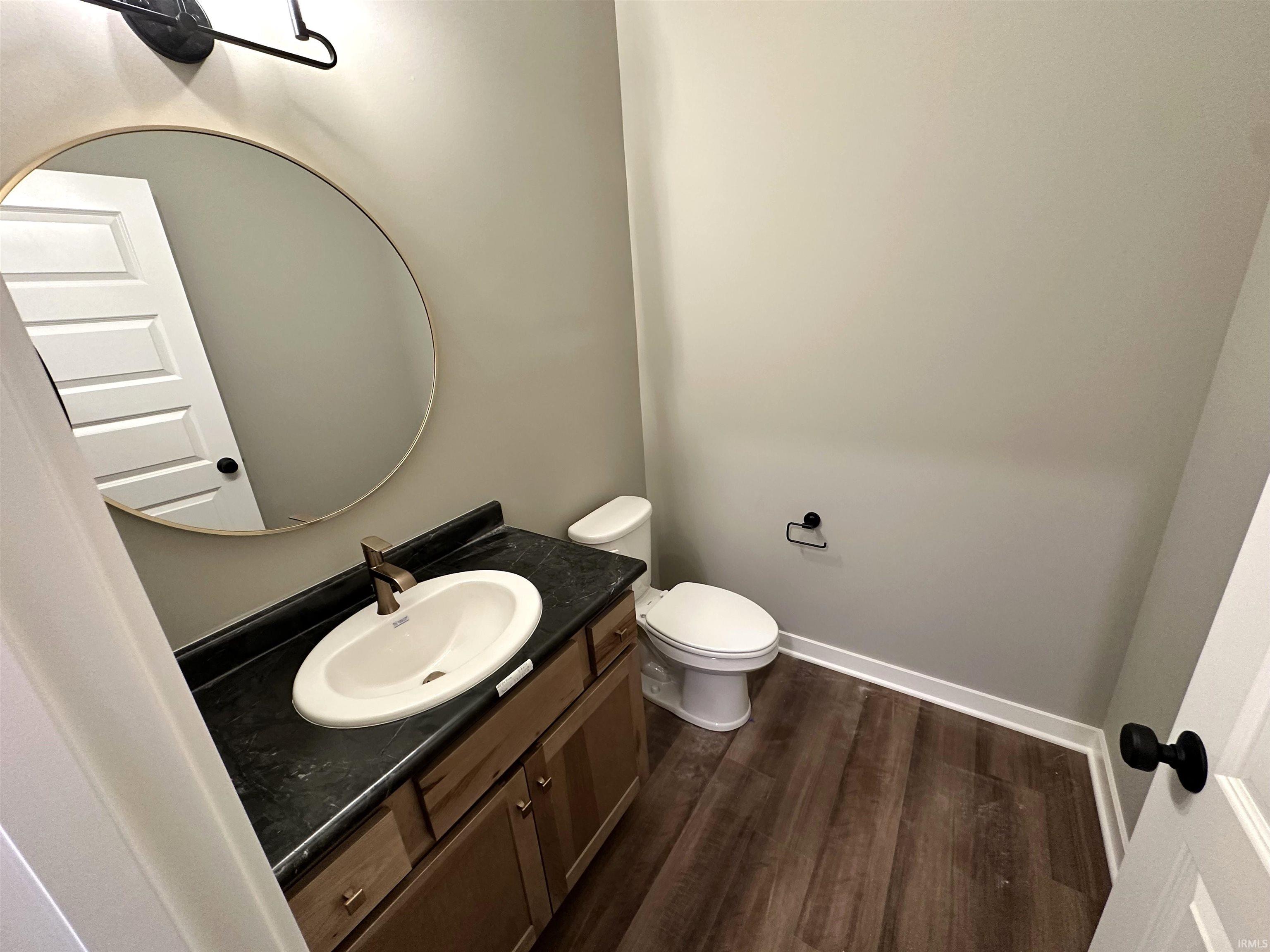 Half bath featuring vanity and dark wood-type flooring