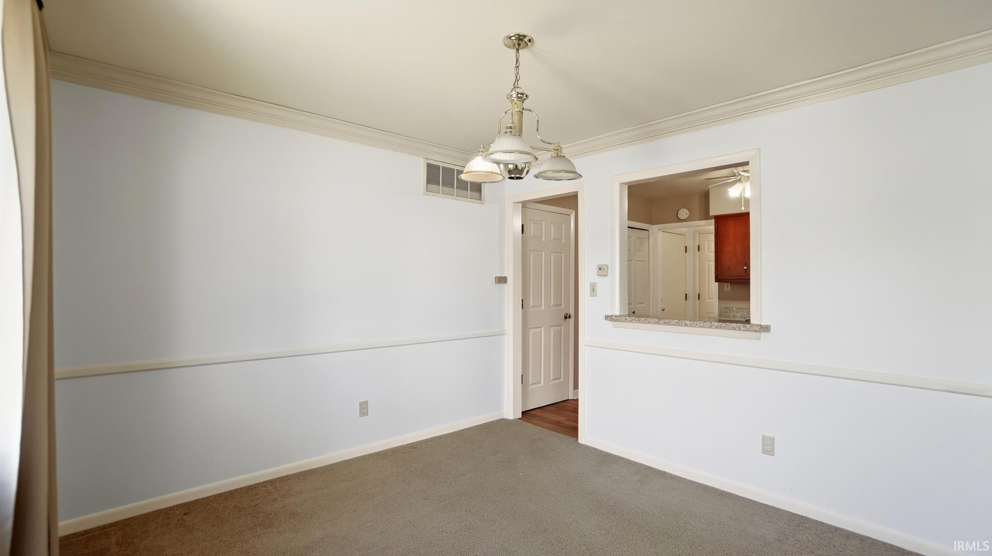 Unfurnished dining area with suspended lighting, crown molding, dark colored carpet, and a ceiling fan