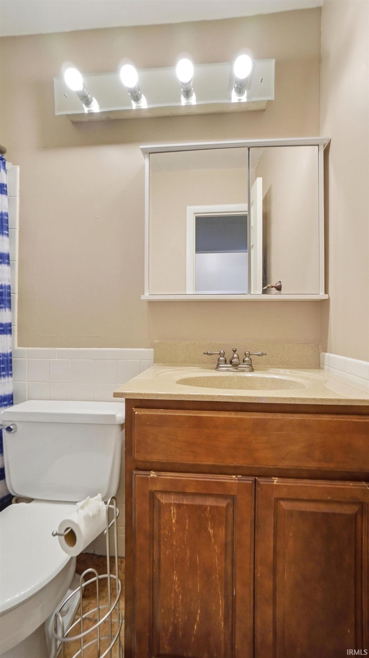 Bathroom with vanity, wainscoting, and a shower with shower curtain