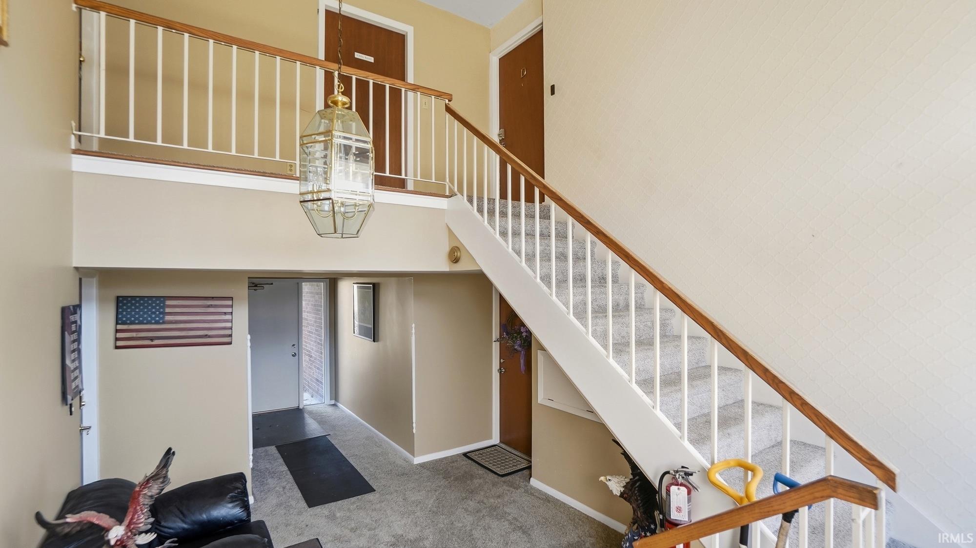Stairway featuring a high ceiling, carpet, and suspended lighting