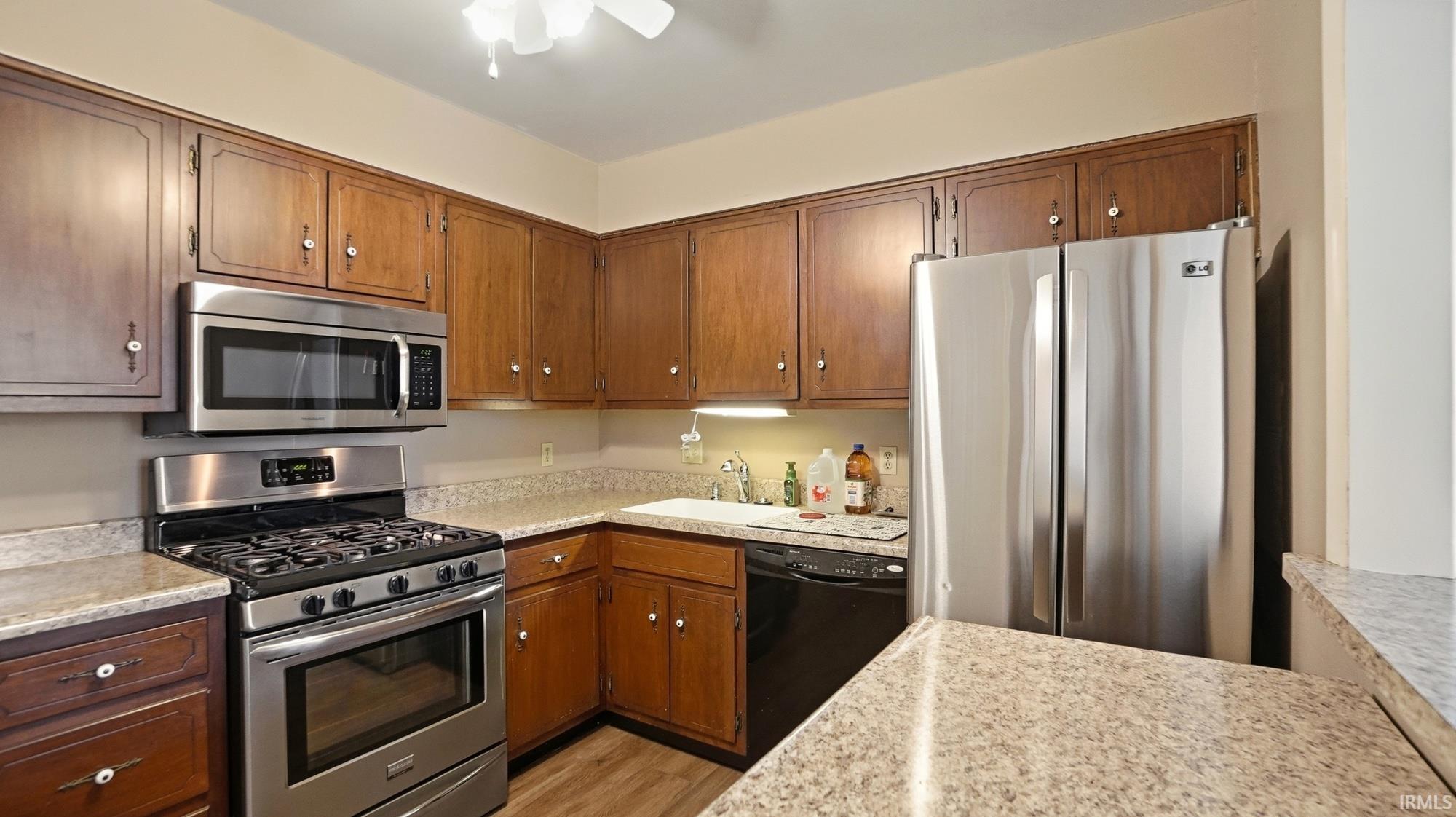 Kitchen with stainless steel appliances, light countertops, wood finish cabinetry, and light wood finished floors