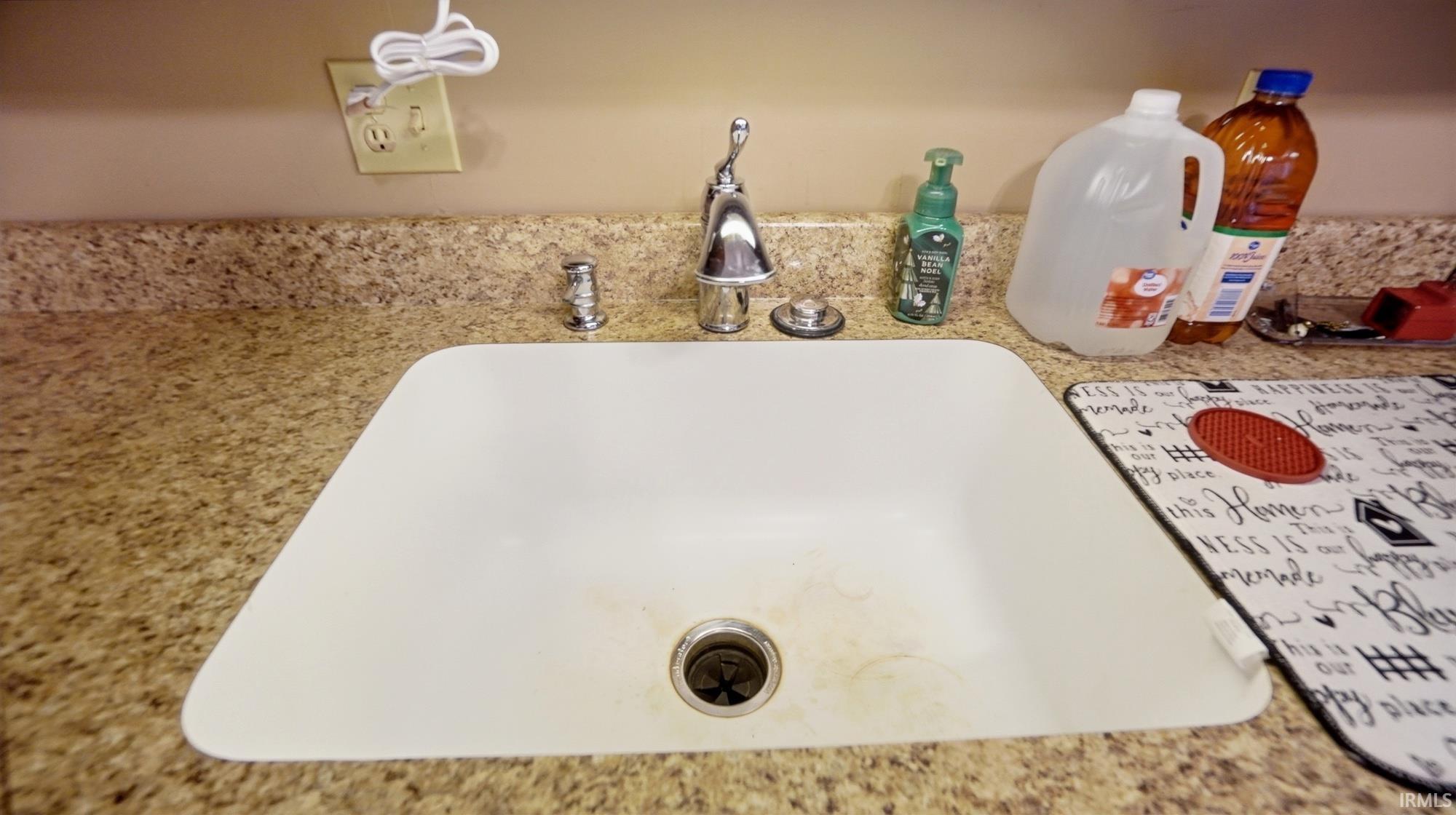 Kitchen view of light stone counters and a sink