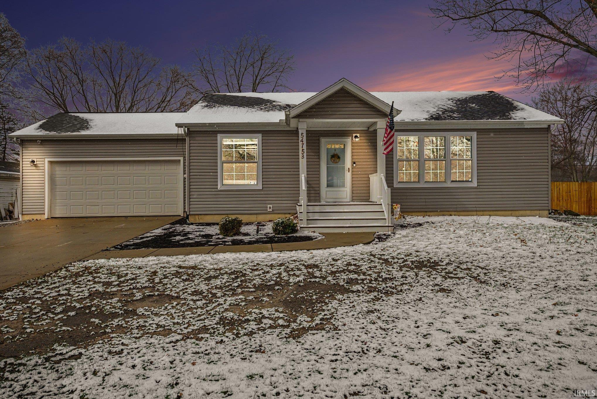 View of front of home with a garage, concrete driveway, and a porch