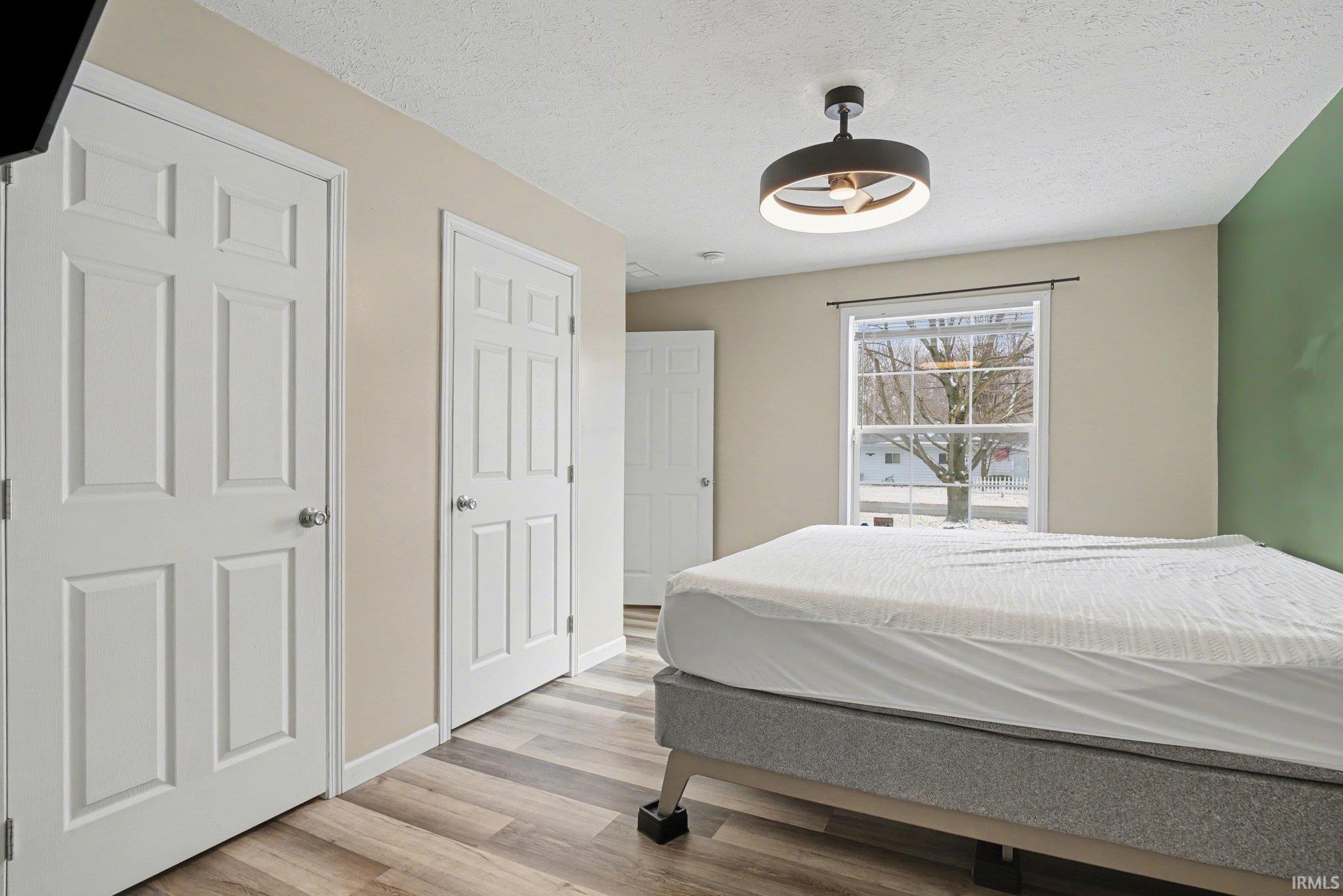 Bedroom featuring multiple closets, light wood-type flooring, and a textured ceiling
