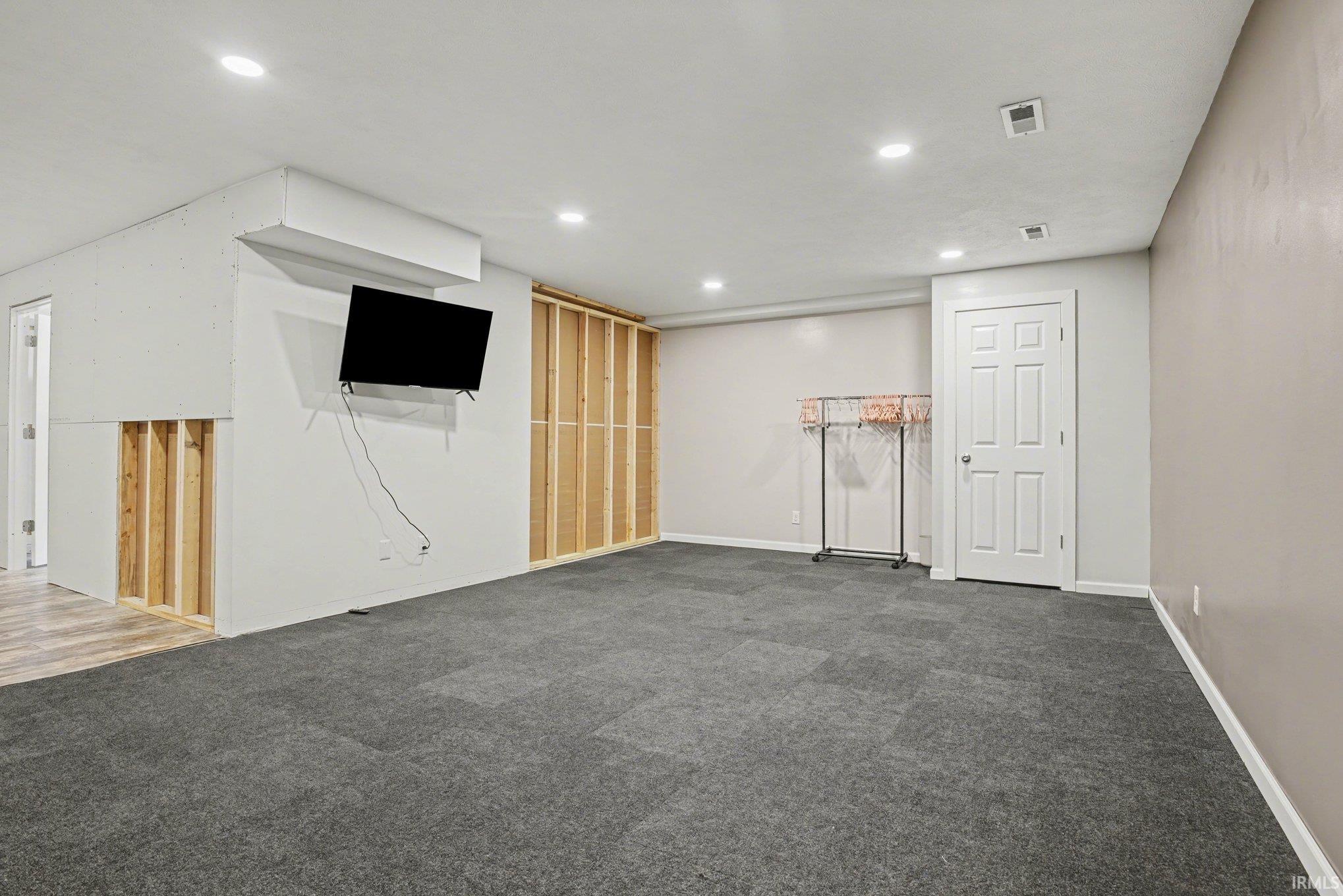 Finished basement featuring dark colored carpet and baseboards