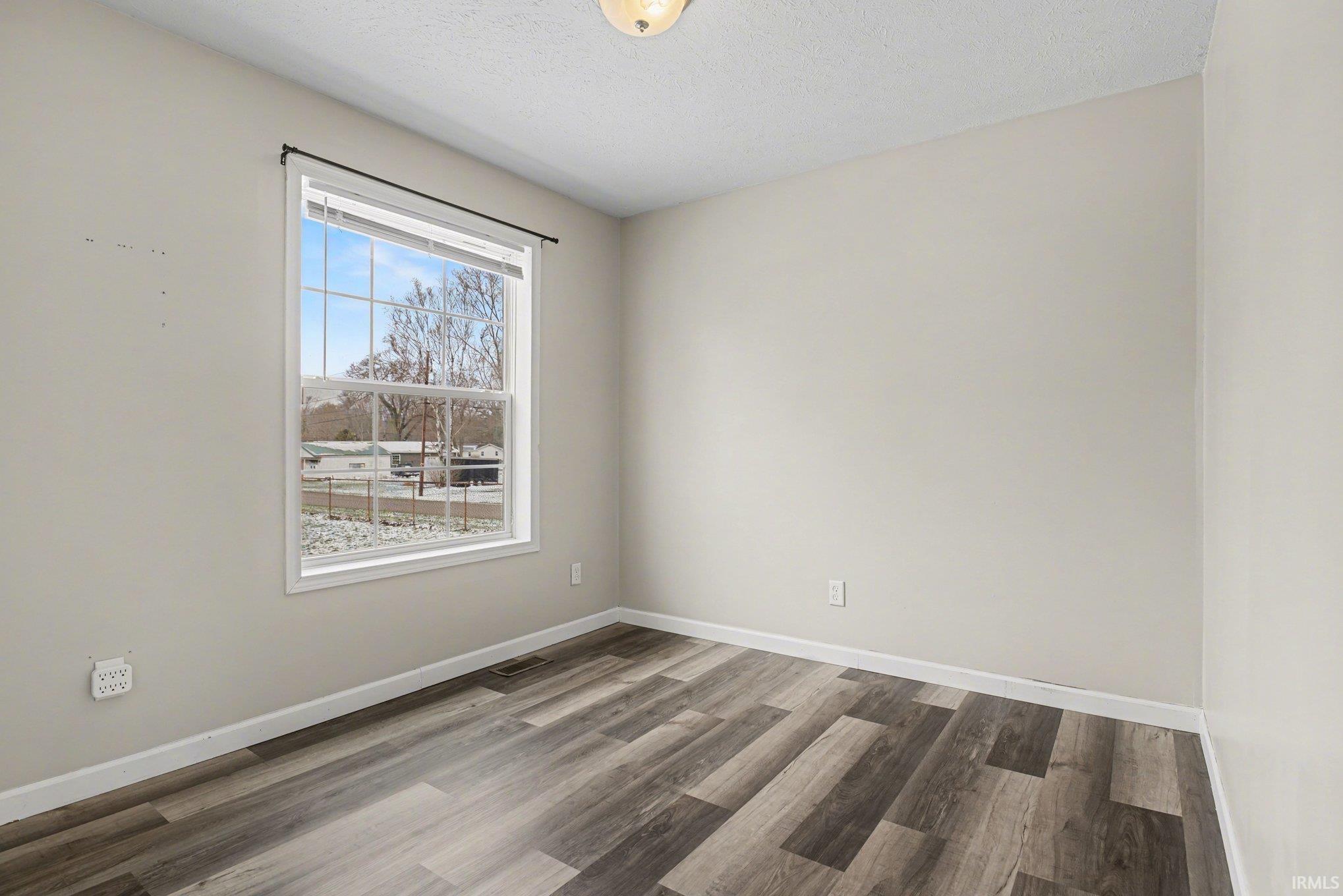 Empty room with wood finished floors and a textured ceiling