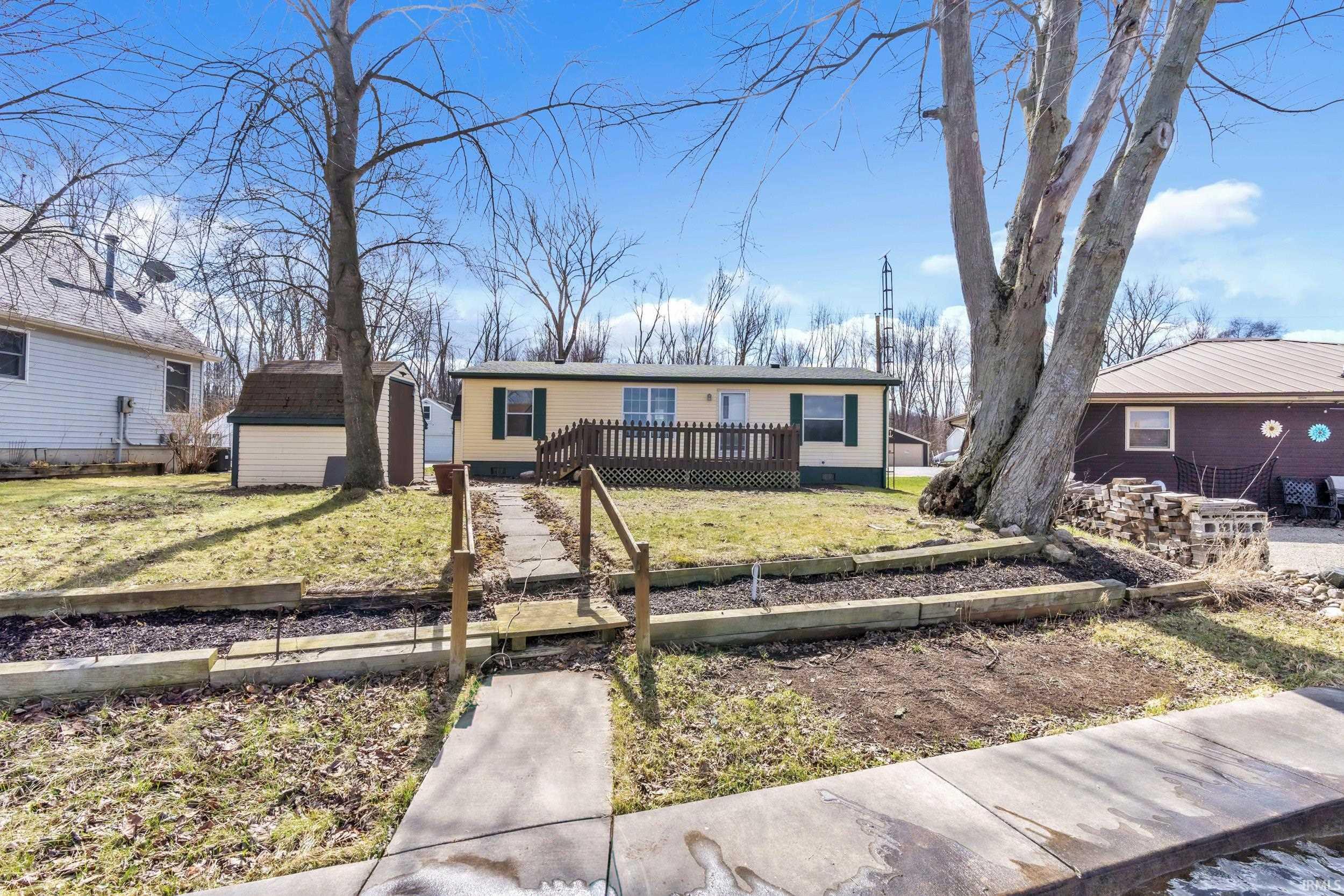 View of front of house with a storage shed, a wooden deck, and a front yard