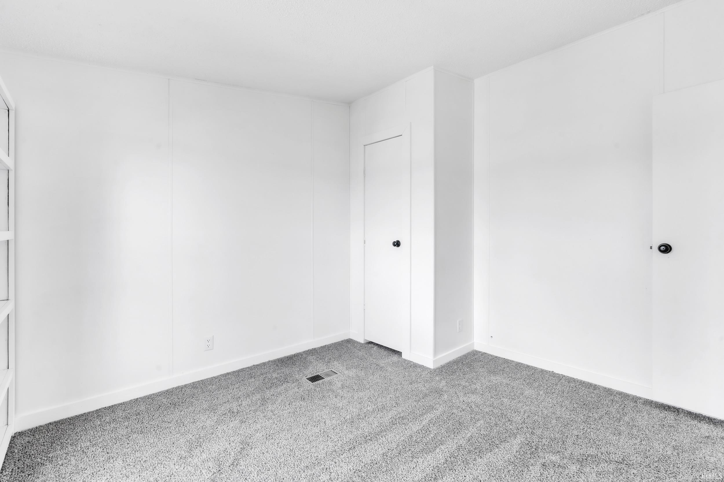 Empty room with light colored carpet and baseboards