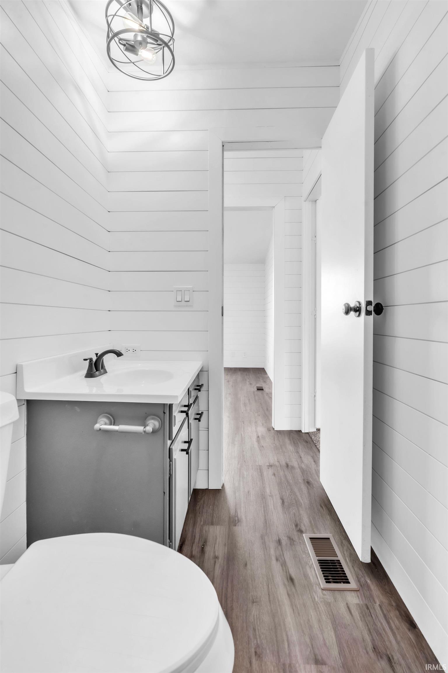 Half bathroom featuring vanity, dark wood-type flooring, and wood walls