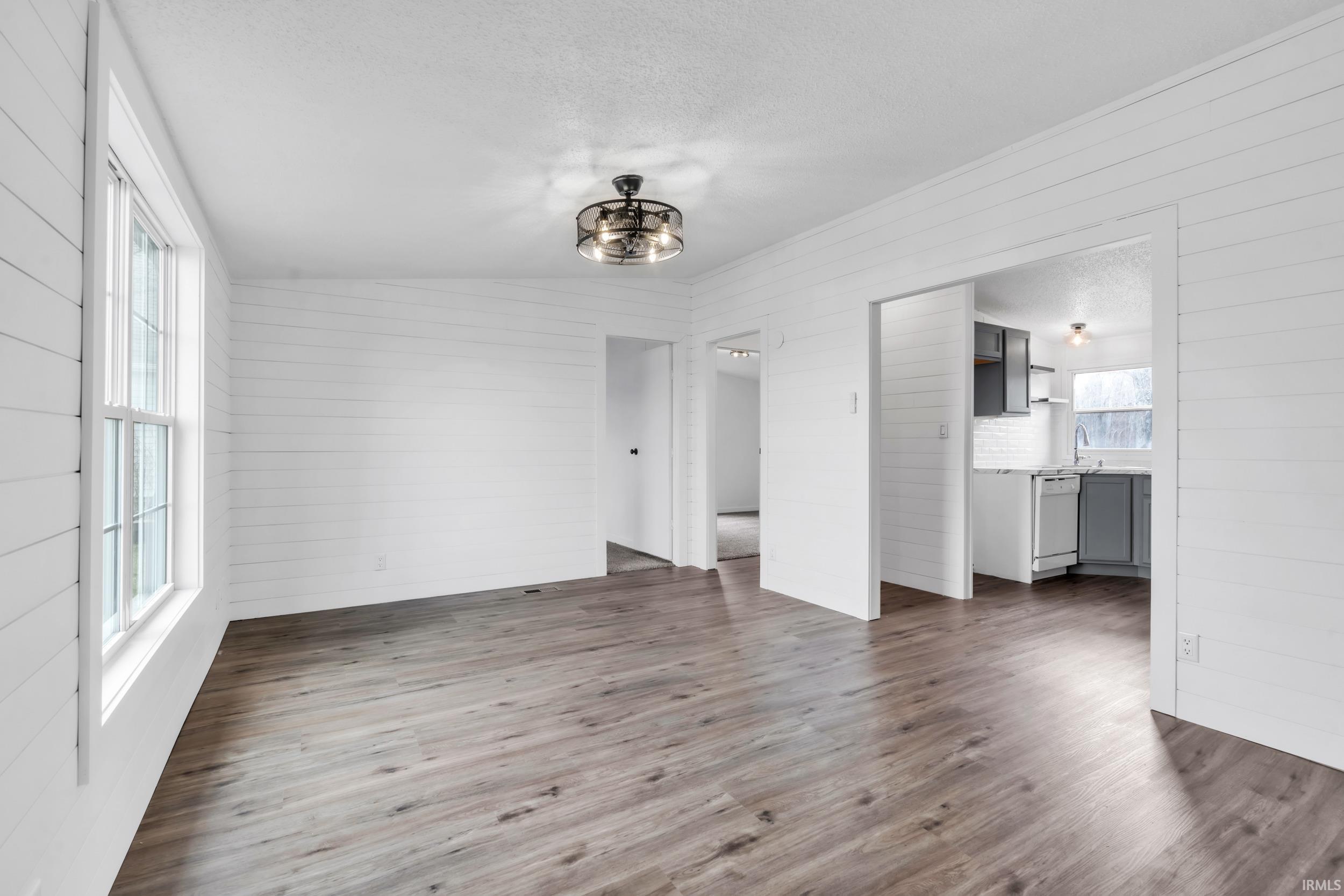 Unfurnished dining area featuring wood walls, dark wood-style flooring, and hanging lights