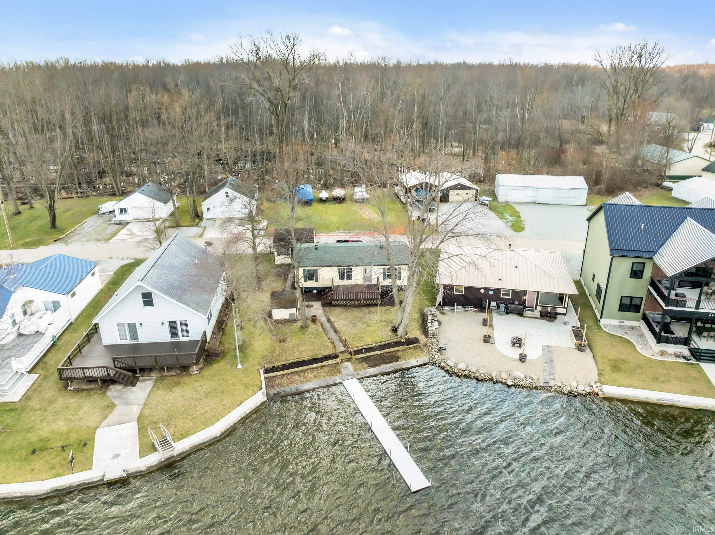 Aerial perspective of suburban area featuring a heavily wooded area and a large body of water
