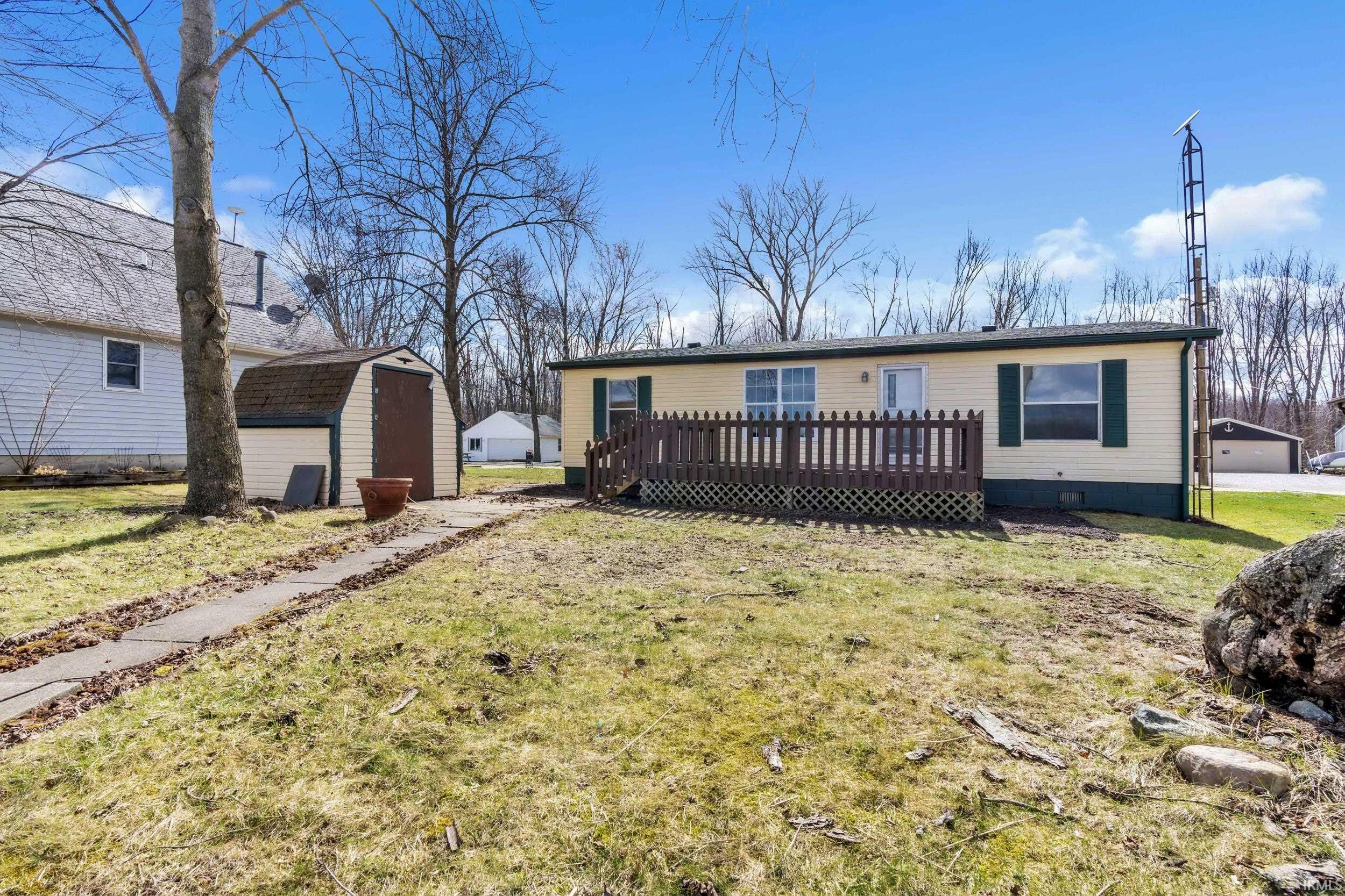 View of front of home featuring a wooden deck, a shed, a front lawn, and a garage