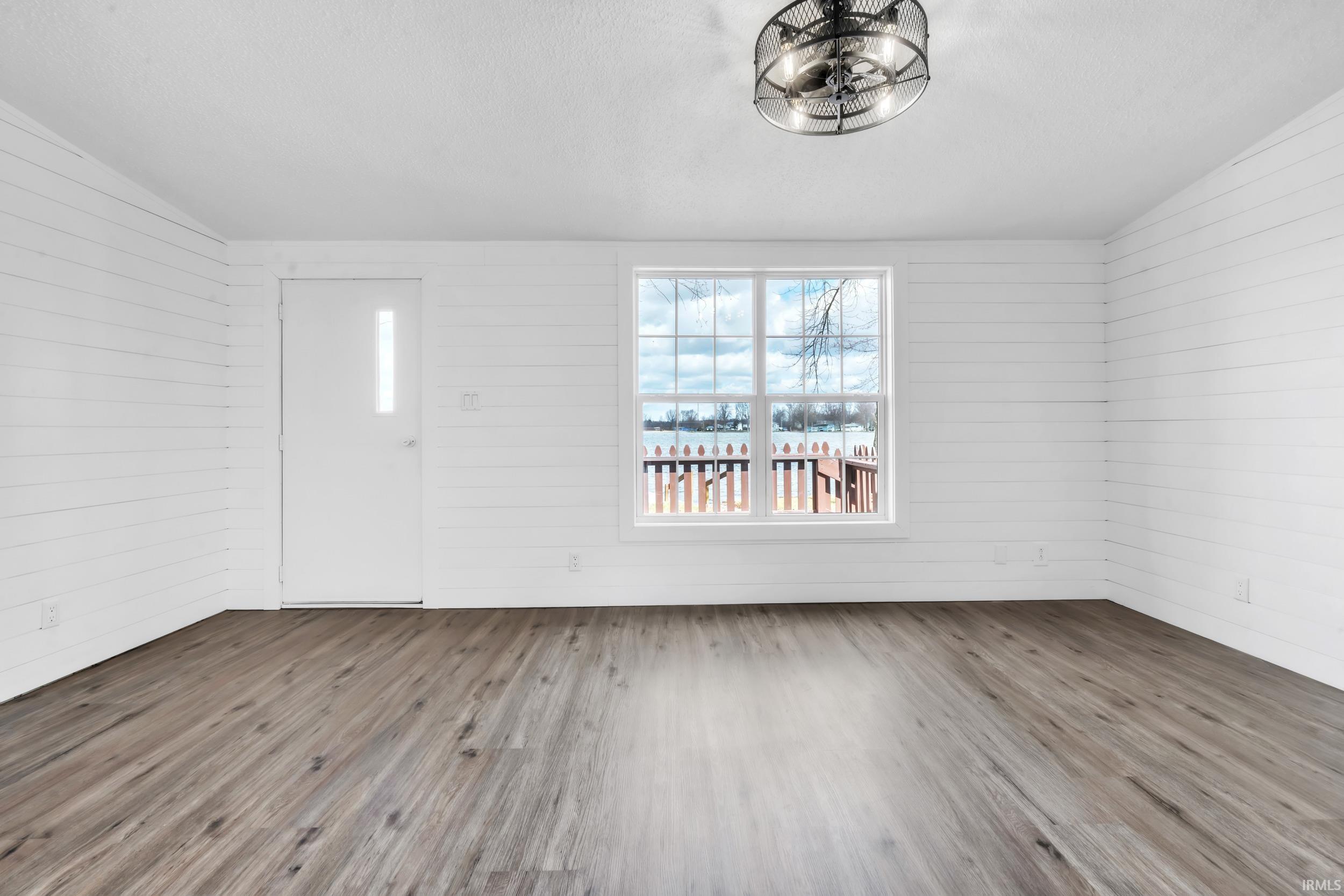 Entrance foyer with wood finished floors, vaulted ceiling, and wood walls