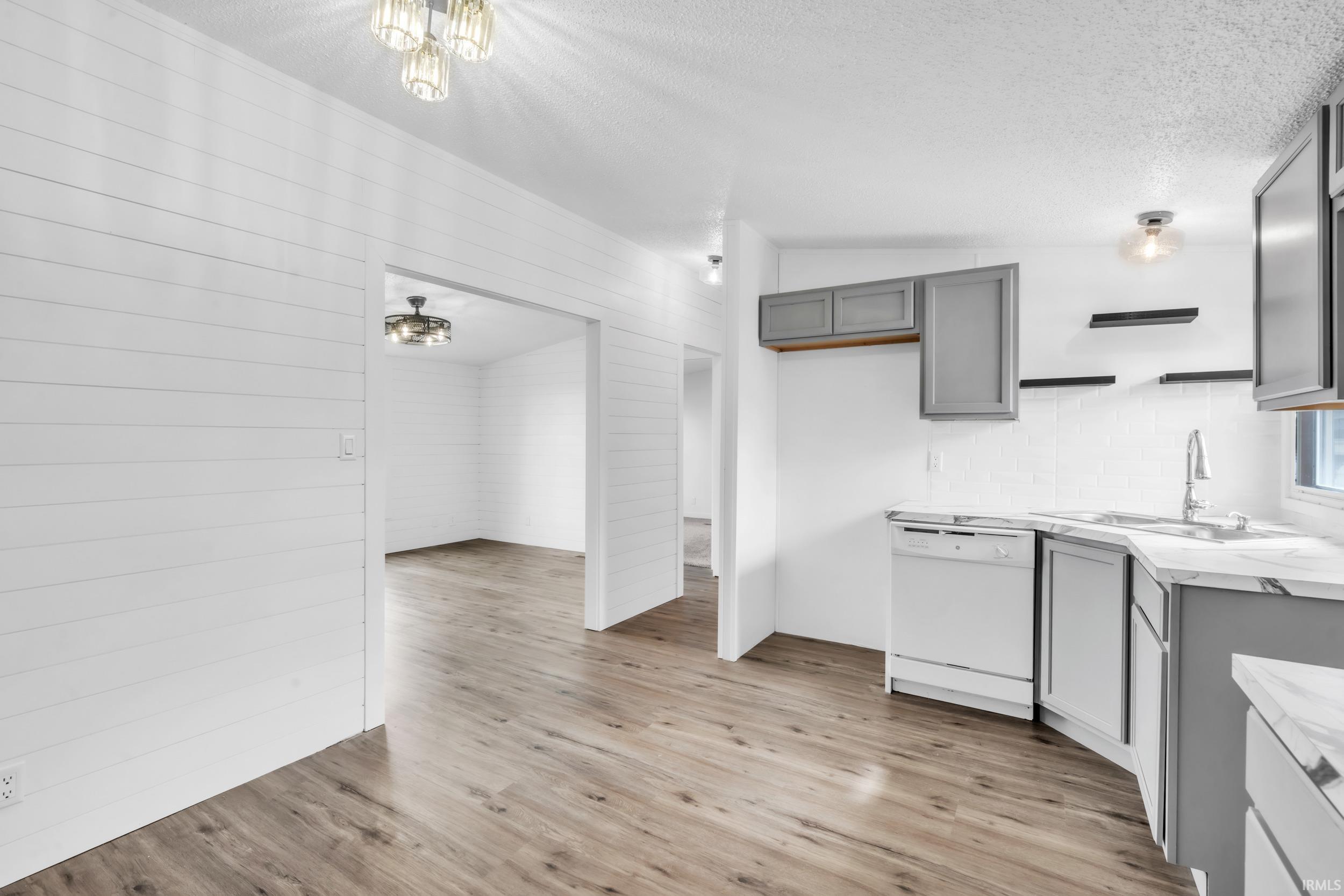 Kitchen with light countertops, dishwasher, a textured ceiling, light wood finished floors, and gray cabinets