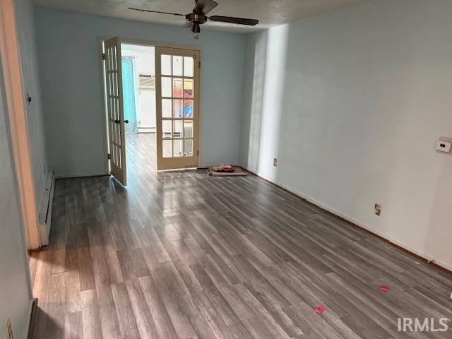 Spare room featuring ceiling fan, dark wood finished floors, and a baseboard heating unit