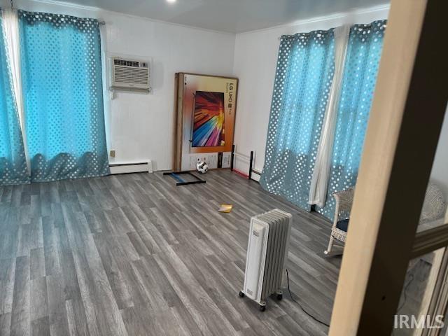 Unfurnished room with radiator heating unit, wood finished floors, and baseboard heating