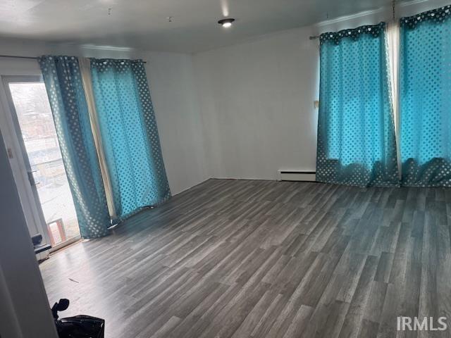 Unfurnished room with dark wood finished floors and baseboard heating