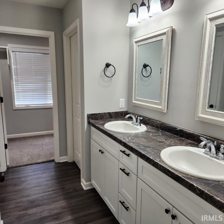 Bathroom with double vanity and dark wood-type flooring