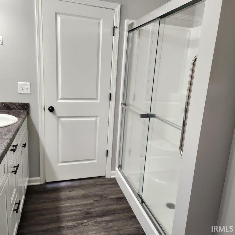 Full bath featuring vanity, a shower stall, and dark wood finished floors