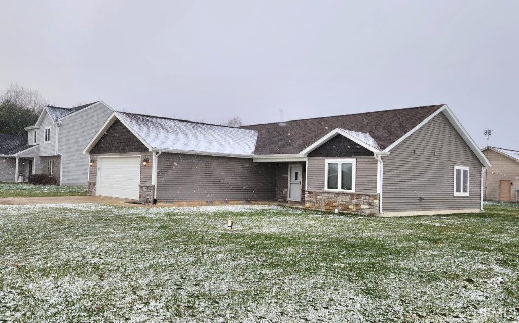 View of front of home with stone siding, a garage, and a front lawn