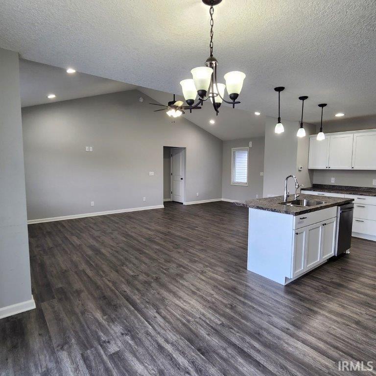 Kitchen with white cabinets, a kitchen island with sink, open floor plan, and dark wood-style floors