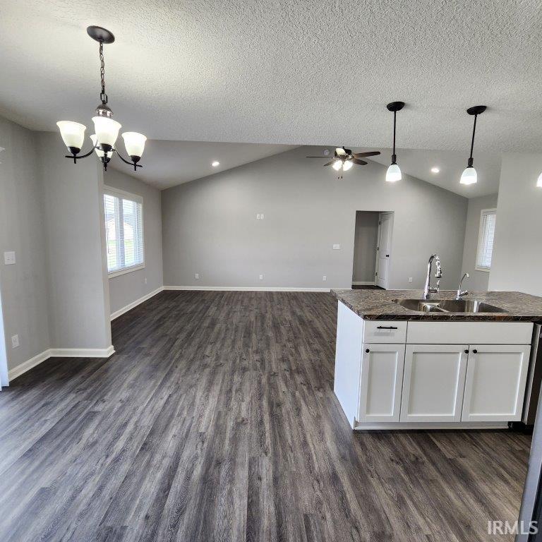 Kitchen featuring open floor plan, white cabinets, dark wood-type flooring, suspended lighting, and ceiling fan